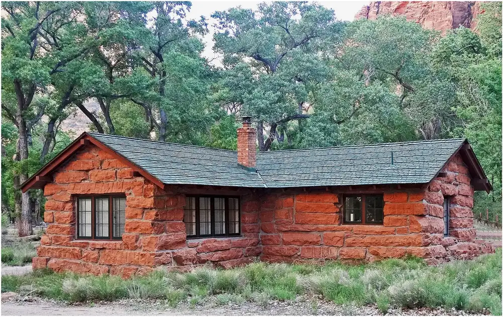 Historische Hütte am Grotto Trail: Bau aus rotem Sandstein mit grünem Schindeldach zwischen Pappeln