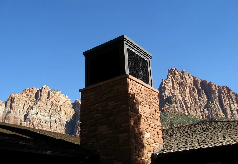 Zion Canyon Visitor Center: Kaminturm aus Sandstein vor den rötlichen Felsgipfeln des Zion Canyon