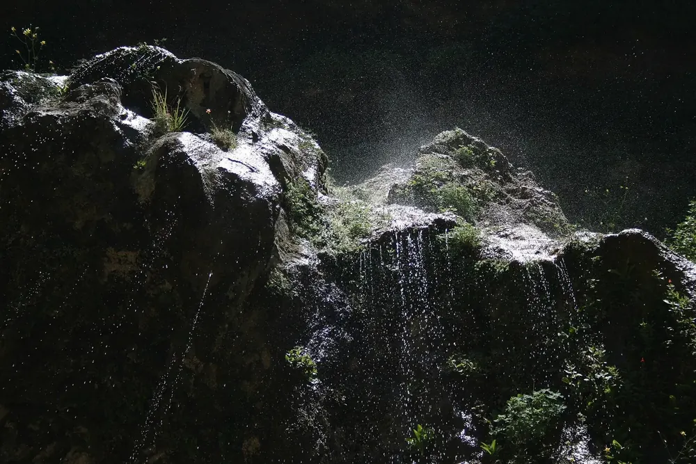 Weeping Rock: Wasser tropft von einem bemoosten, überhängenden Sandsteinfelsen im Gegenlicht
