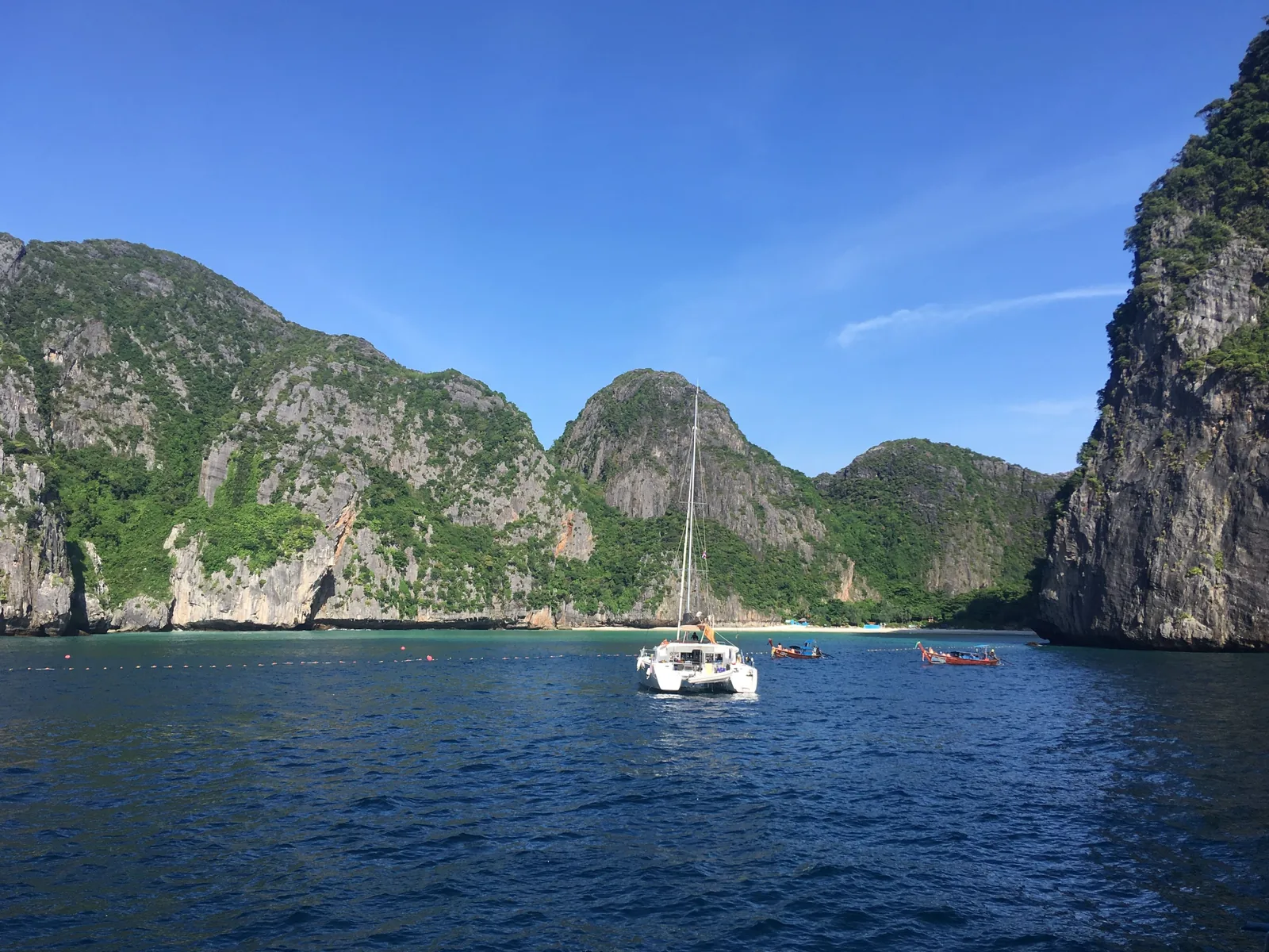 Die Maya Bay im Juni 2018, fünf Tage nach ihrer Schließung: ein Katamaran auf dunkelblauem Wasser vor bewaldeten Kalkbergen
