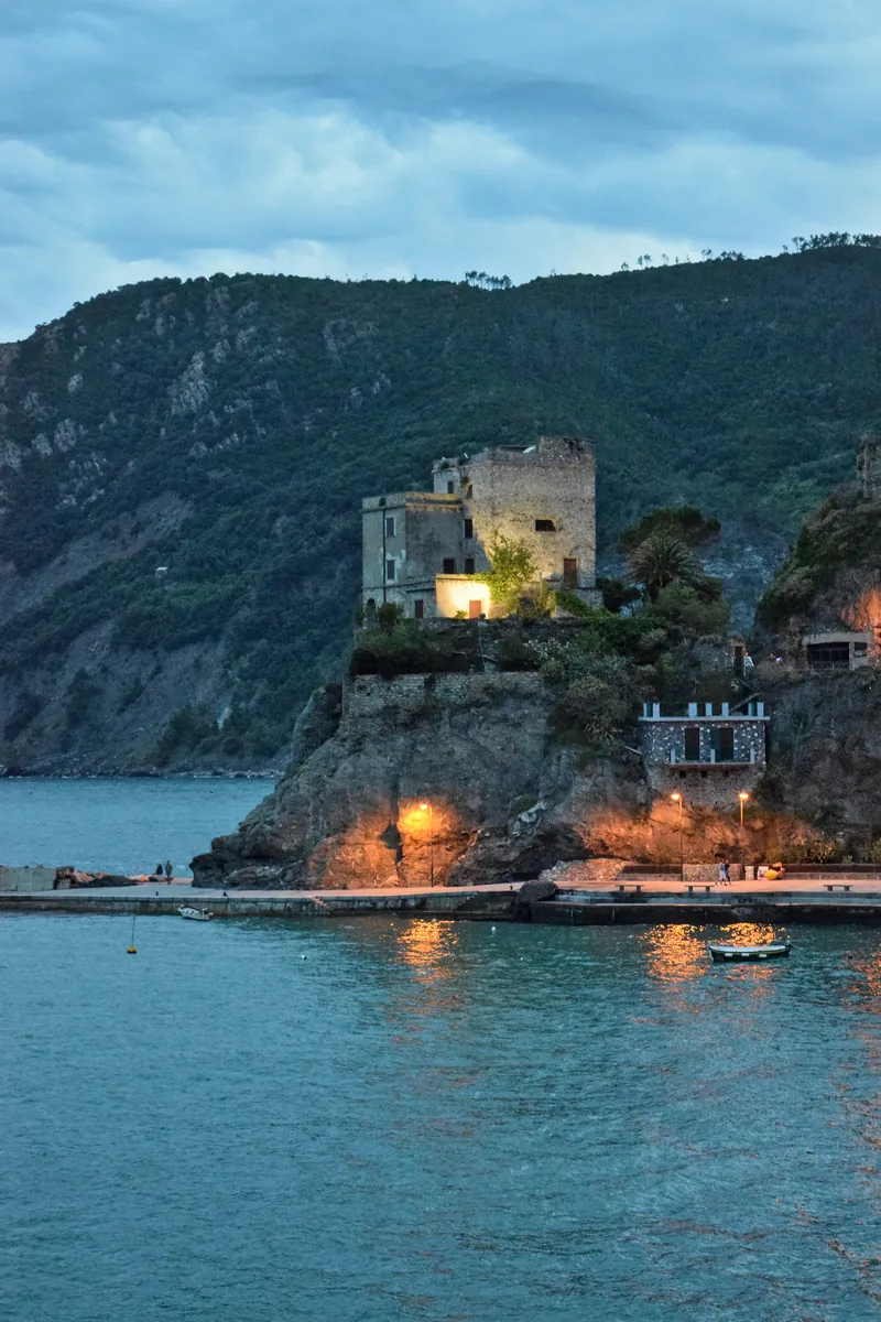 Die Torre Aurora in Monterosso al Mare auf ihrem Felsen über dem Wasser, abends beleuchtet