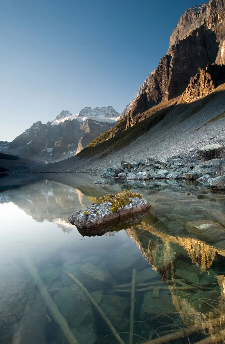 Stilles Wasser des Lower Consolation Lake mit Felsen und gespiegelter Bergflanke