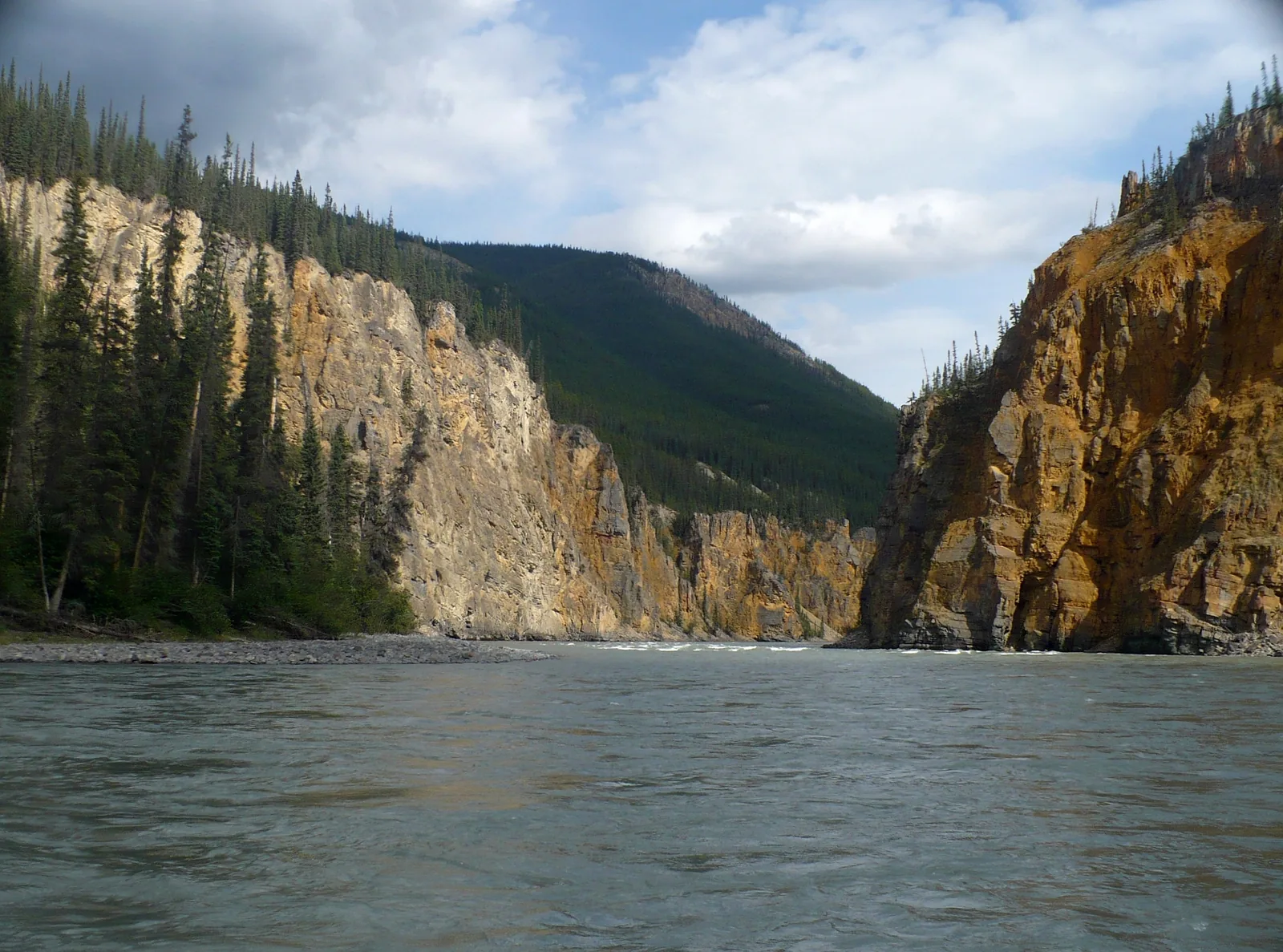 Blick vom Wasser aus in den Vierten Canyon: hohe geschichtete Felswände zu beiden Seiten, der Fluss zieht ruhig dazwischen hindurch