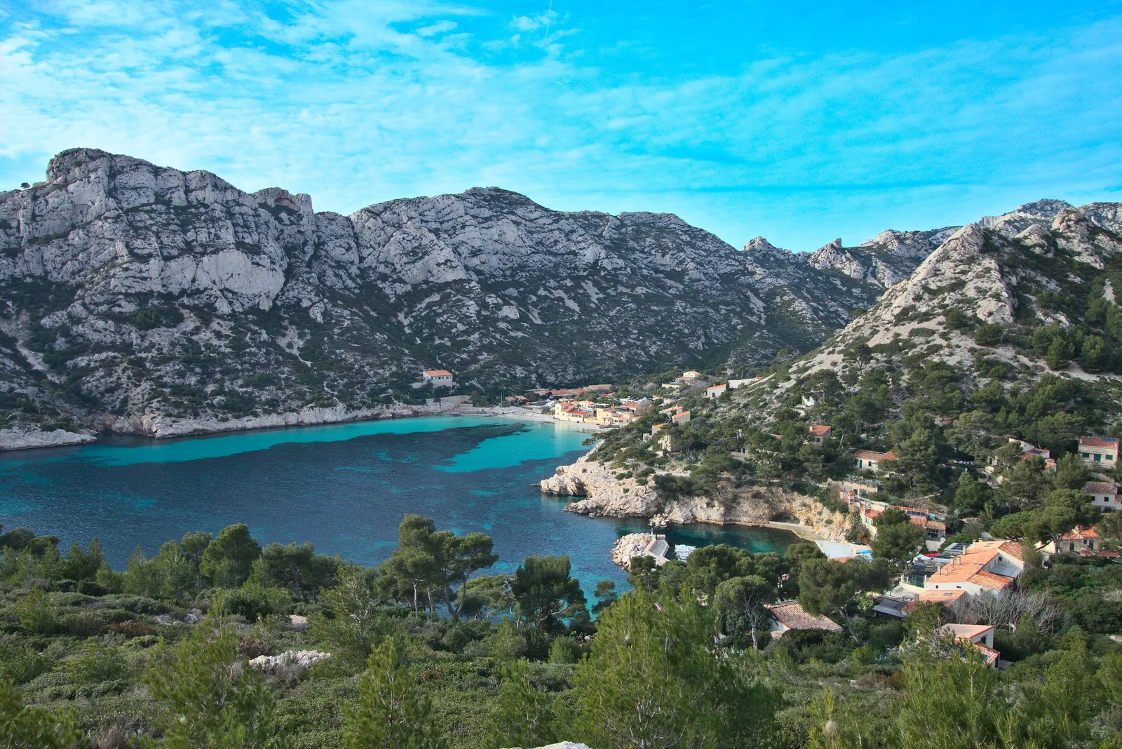 Die Calanque de Sormiou im Nationalpark Calanques vom Grat von Morgiou: türkise Bucht, Strand, Häuschen und Kalkberge