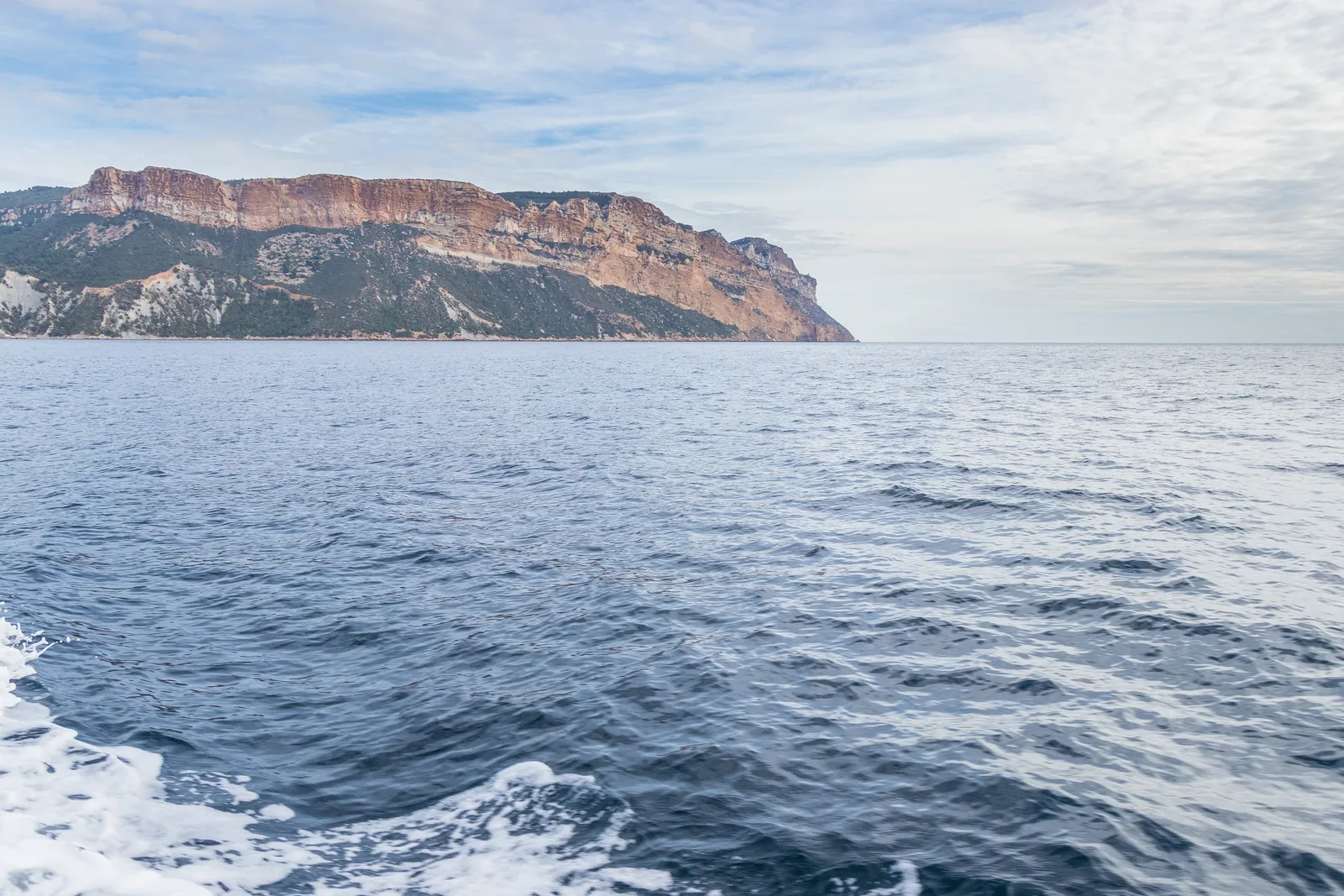 Das Cap Canaille im Nationalpark Calanques vom Meer vor Cassis aus: rötliche Klippen über dem blauen Wasser