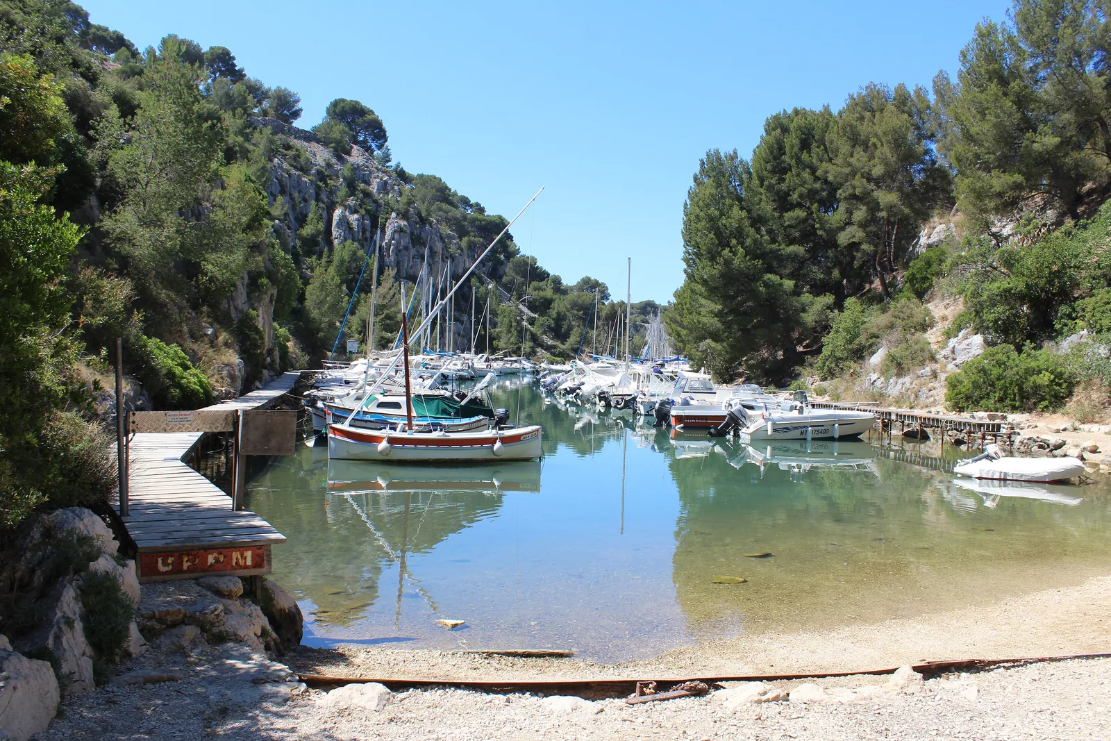 Die Calanque de Port-Miou bei Cassis im Nationalpark Calanques: Segelboote am Steg, klares Wasser und Kiefern an den Felsen