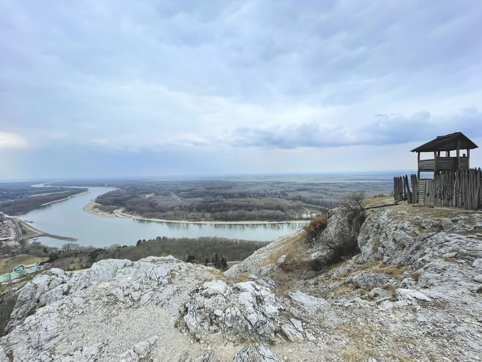 Blick vom Braunsberg über die Donau und die Auwälder des Nationalparks Donau-Auen, vorn Kalkfelsen und ein hölzerner Aussichtsturm