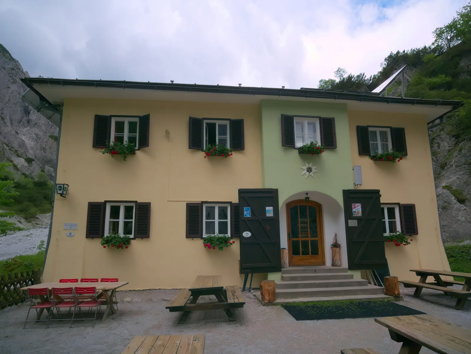 Die Haindlkarhütte des Alpenvereins im Nationalpark Gesäuse mit Holzbänken vor der gelben Fassade