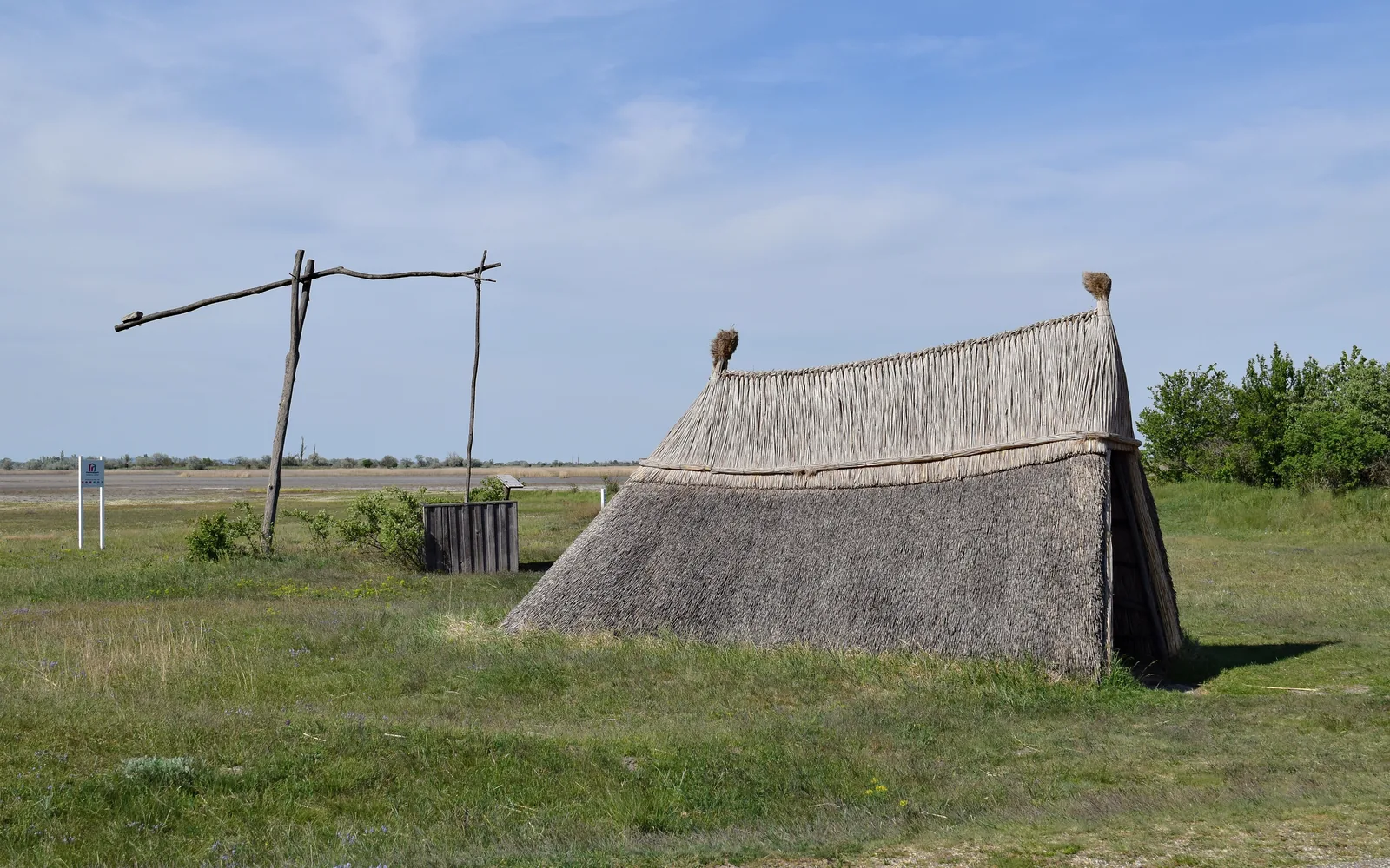 Ziehbrunnen und eine Schilfhütte am Ufer der Zicklacke bei Illmitz im Nationalpark Neusiedler See – Seewinkel