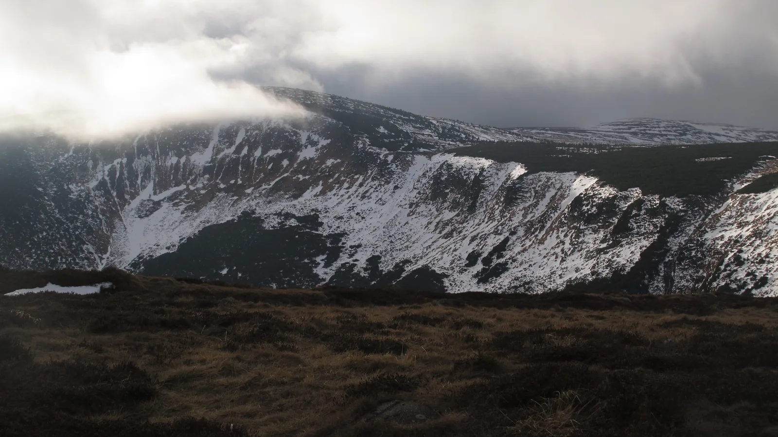 Der Riesengrund im Nationalpark Riesengebirge mit Herbstschnee an den steilen Hängen unter tiefen Wolken