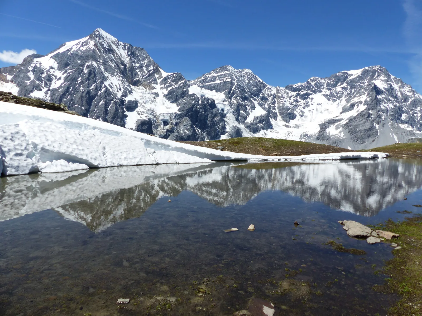Königspitze, Zebrù und Ortler im Nationalpark Stilfserjoch spiegeln sich in einem kleinen Bergsee mit Schneeresten