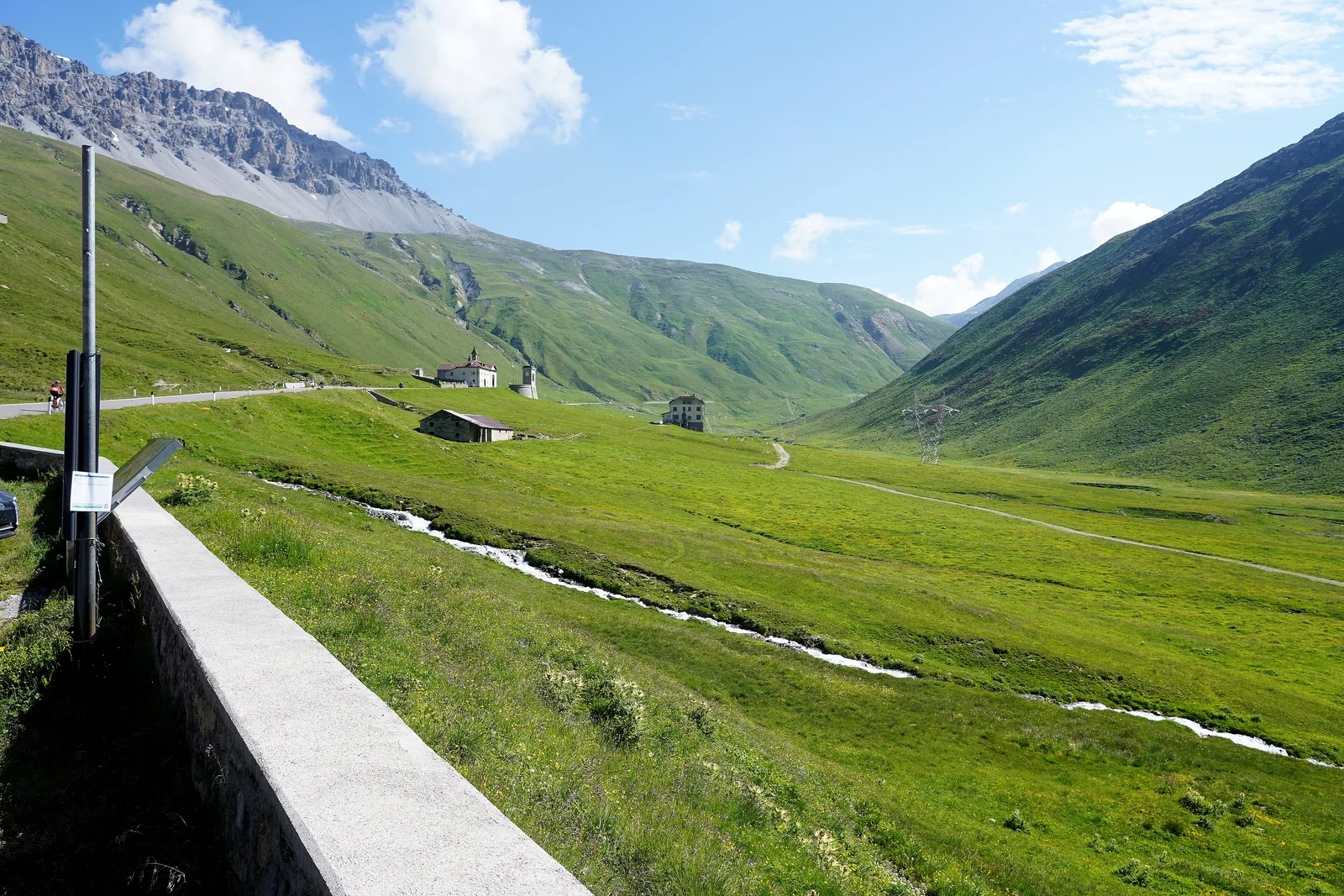 Das grüne Hochtal Valle del Braulio im Nationalpark Stilfserjoch westlich der Passhöhe, mit Straßenmauer und Bach