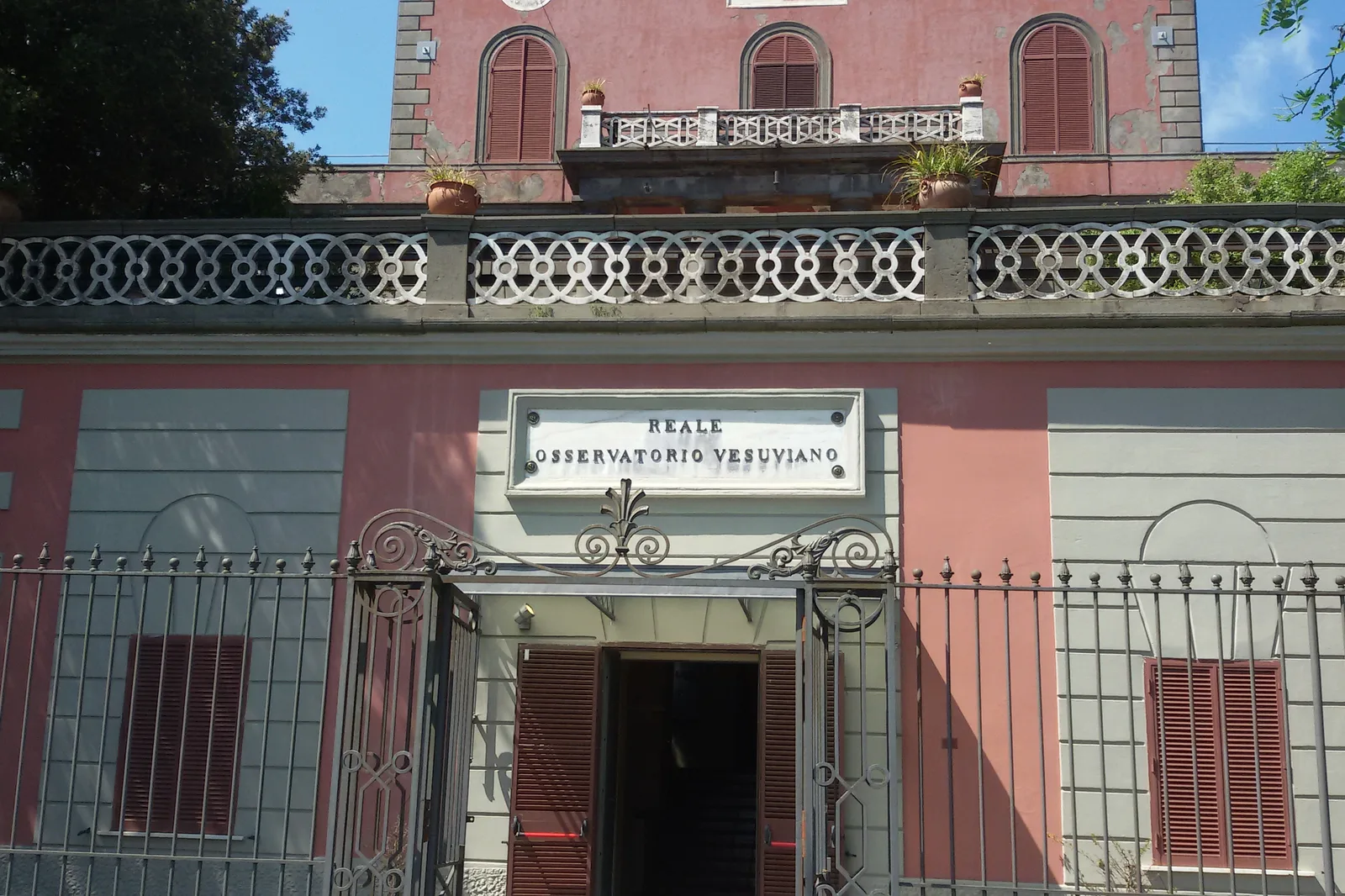 Eingang des Reale Osservatorio Vesuviano im Nationalpark Vesuv mit rosa Fassade und schmiedeeisernem Tor