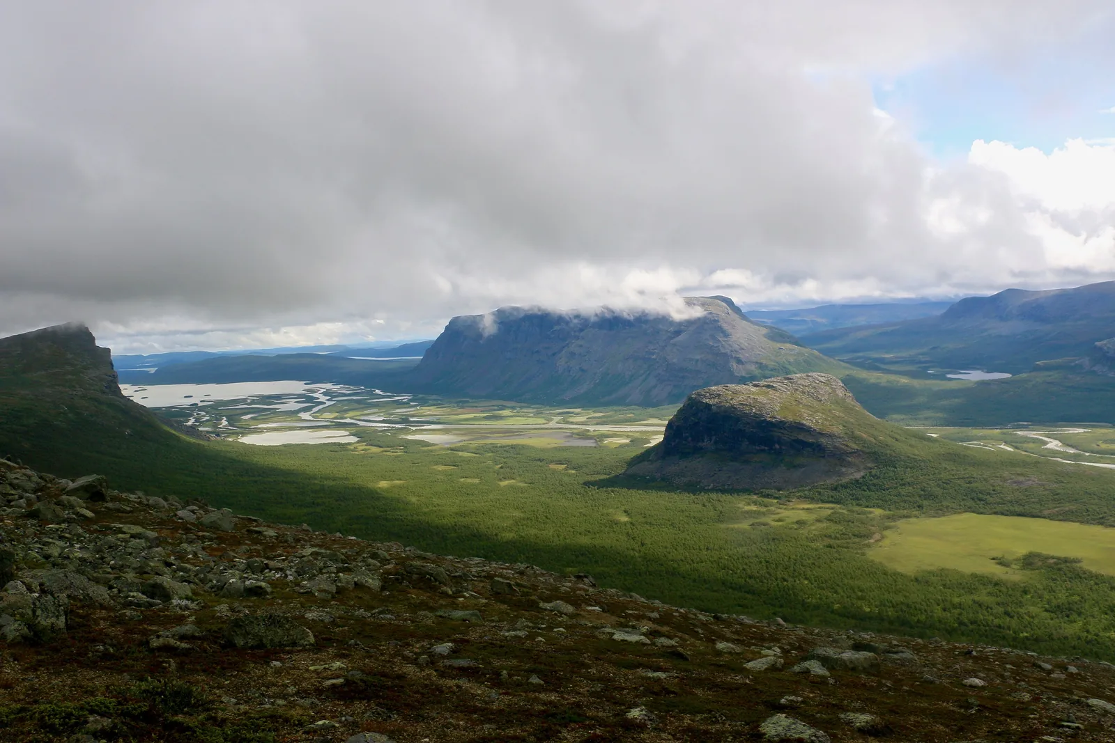 Der Inselberg Nammásj über dem grünen Delta des Rapaätno im Sarek-Nationalpark, im Hintergrund der Lájtávrre und Wolken über den Bergen