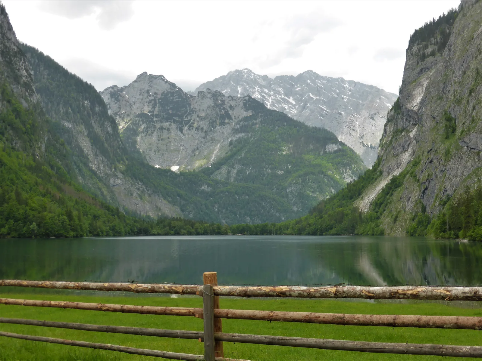 Blick von der Fischunkelalm über den Obersee mit Holzzaun zu den Bergen des Nationalparks Berchtesgaden