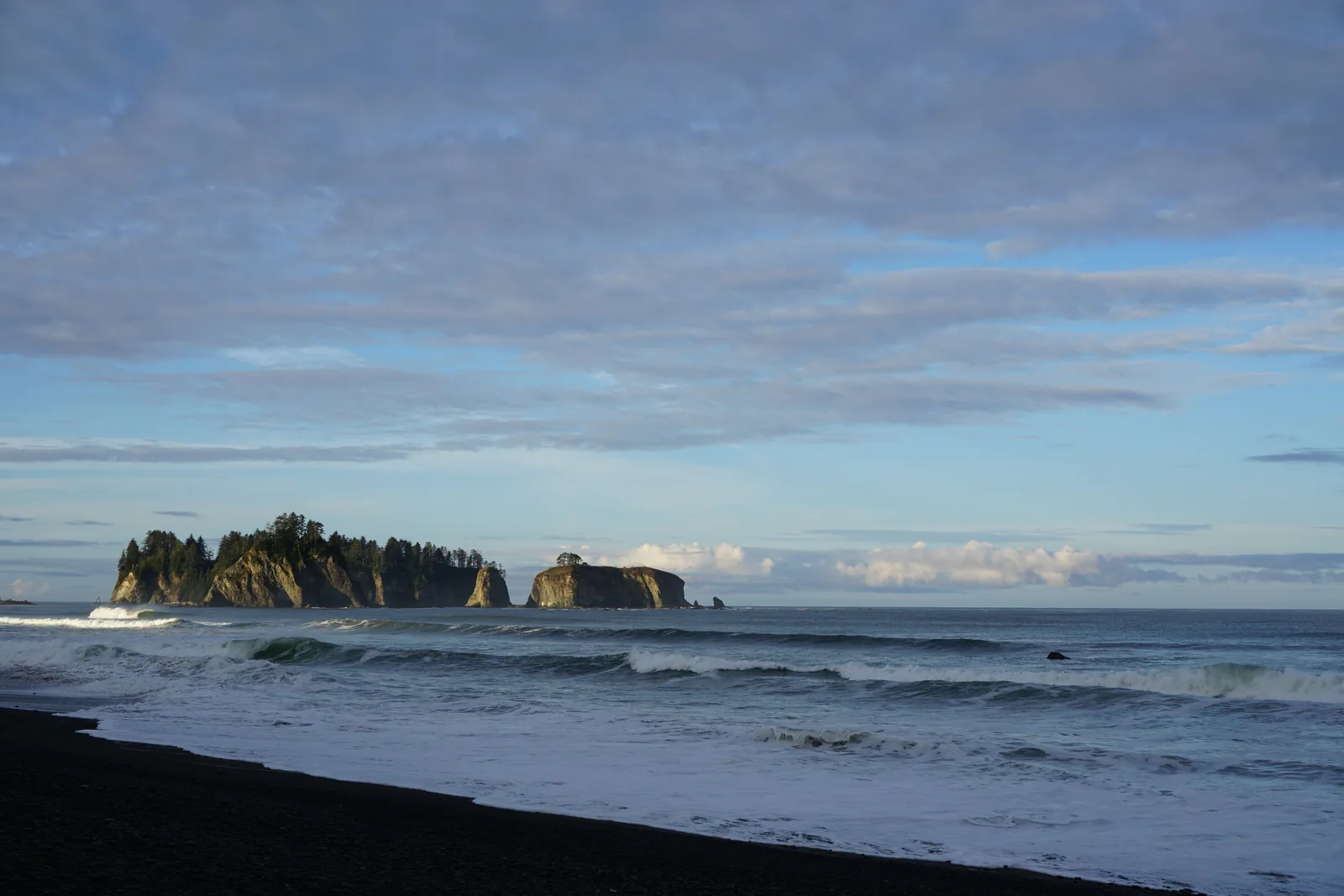 Rialto Beach am Morgen: schwarzer Kiesstrand, Brandung und die bewaldete Felsinsel James Island