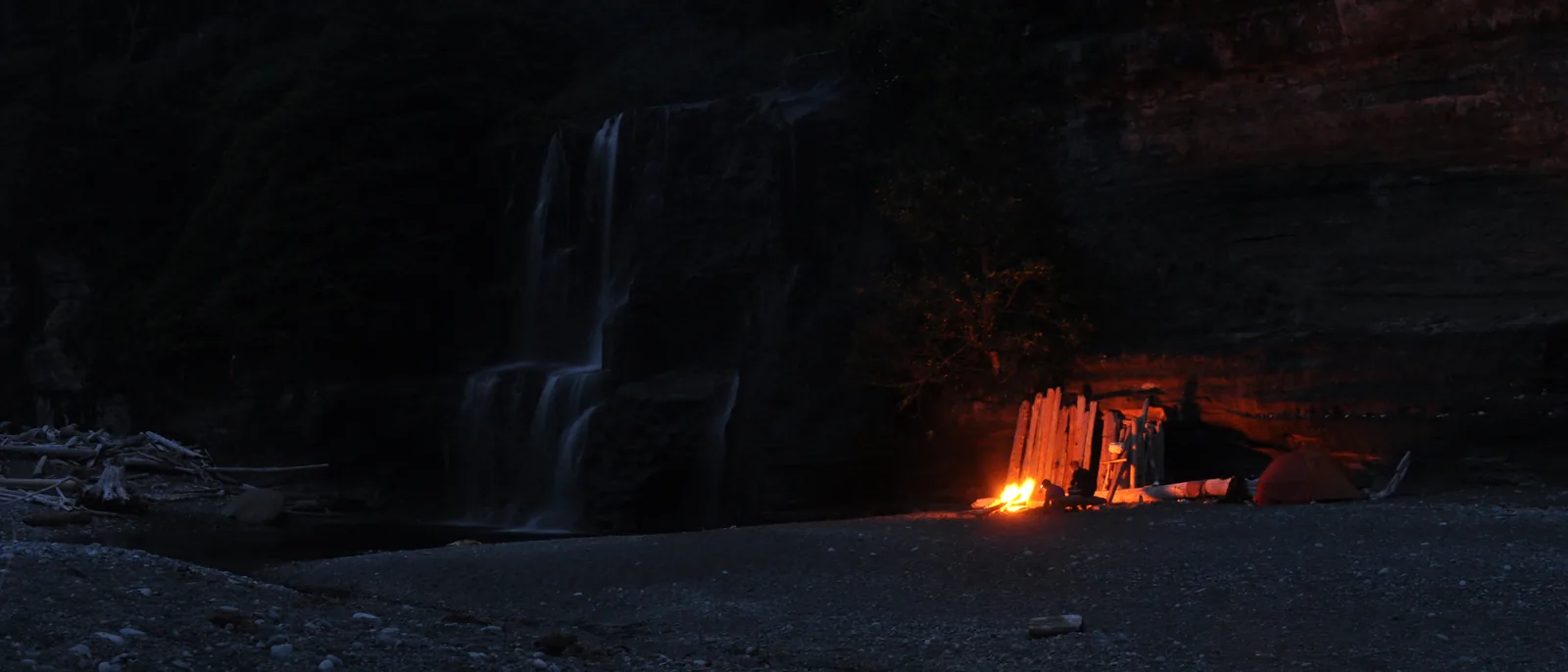 Nachtaufnahme am Lagerplatz Tsusiat Falls: links der Wasserfall, rechts der Schein eines Lagerfeuers unter dem Felsüberhang