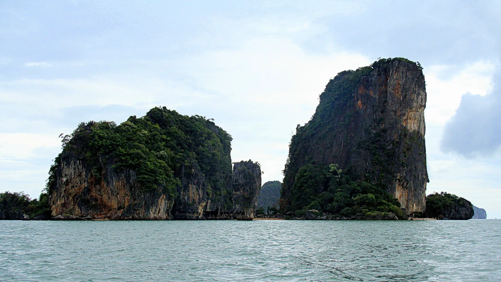Die bewachsenen Kalkfelsen von Khao Phing Kan im Nationalpark Ao Phang Nga, rechts davon der hohe Felsturm, vom Wasser aus gesehen
