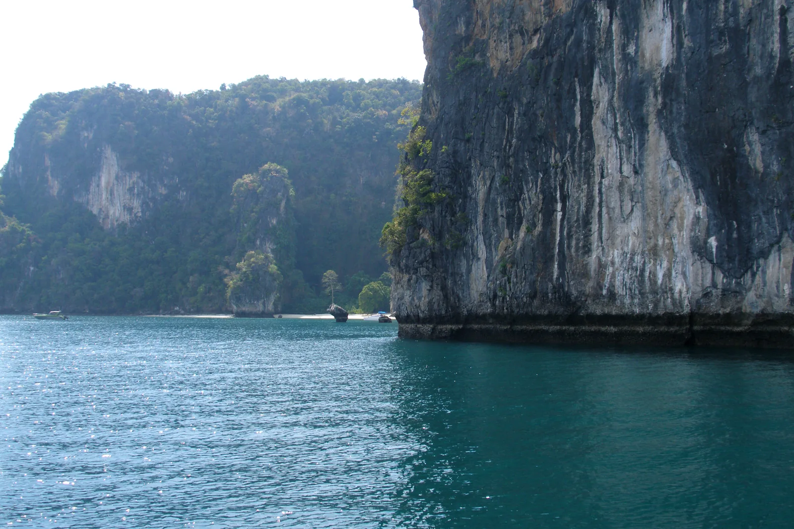 Dunkelgrünes Wasser vor einer senkrechten Kalkwand bei Ko Hong im Nationalpark Ao Phang Nga, dahinter weitere bewachsene Felsen