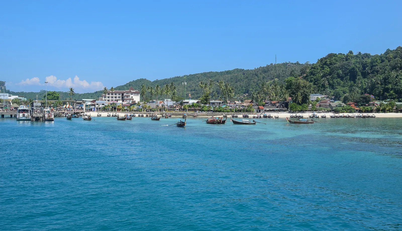 Die Bucht von Ton Sai auf Ko Phi Phi Don mit Booten vor dem Ufer, Häusern am Strand und bewaldeten Hügeln dahinter