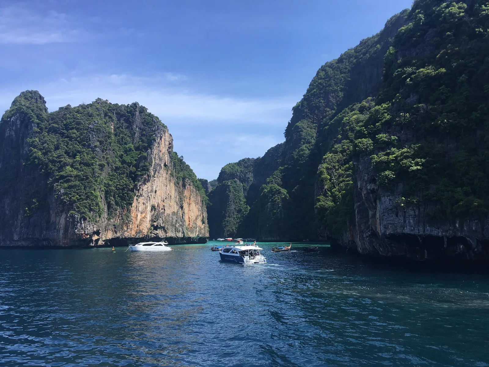 Zwei Schnellboote fahren im Phi-Phi-Nationalpark in die Pileh-Lagune ein, zwischen hohen, bewachsenen Kalkfelsen