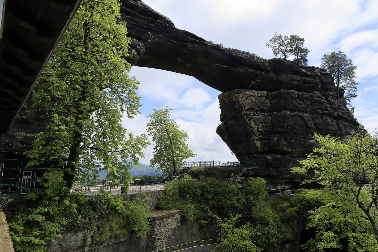 Durch den Bogen des Prebischtors fällt der Blick nach Südosten, links ein Felspfeiler, unten Geländer der Aussichtswege