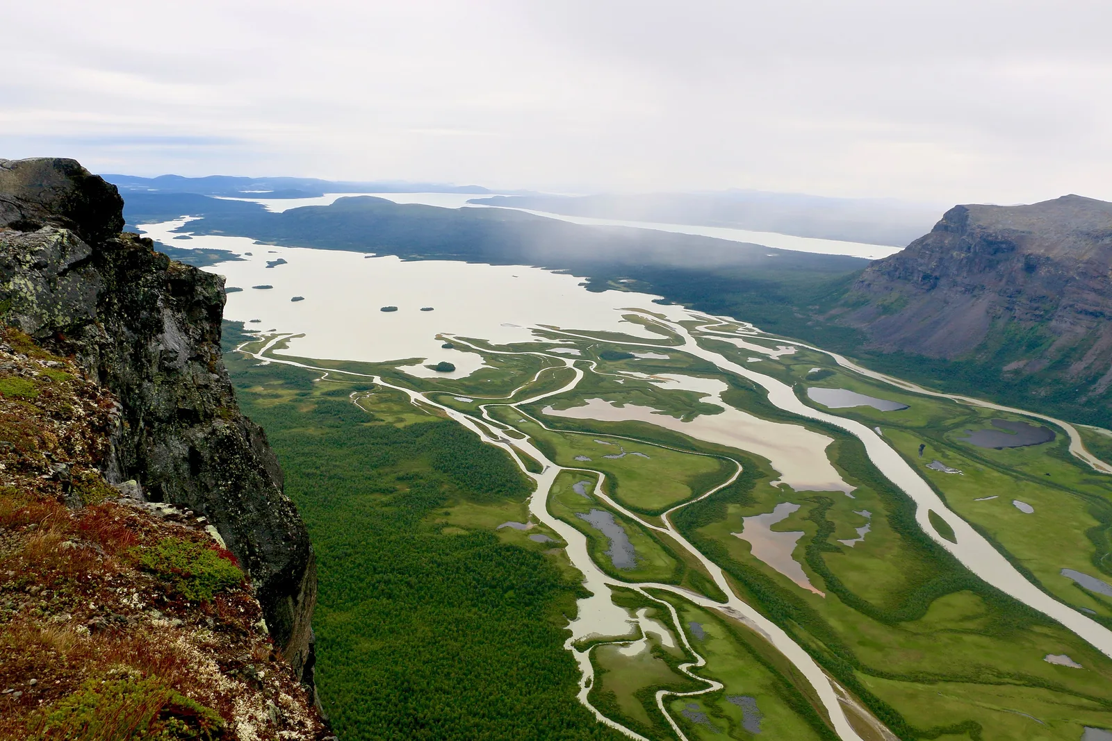 Blick vom Skierffe am Rand des Sarek-Nationalparks auf das verzweigte Delta des Rapaätno im Lájtávrre, rechts eine steile Bergflanke