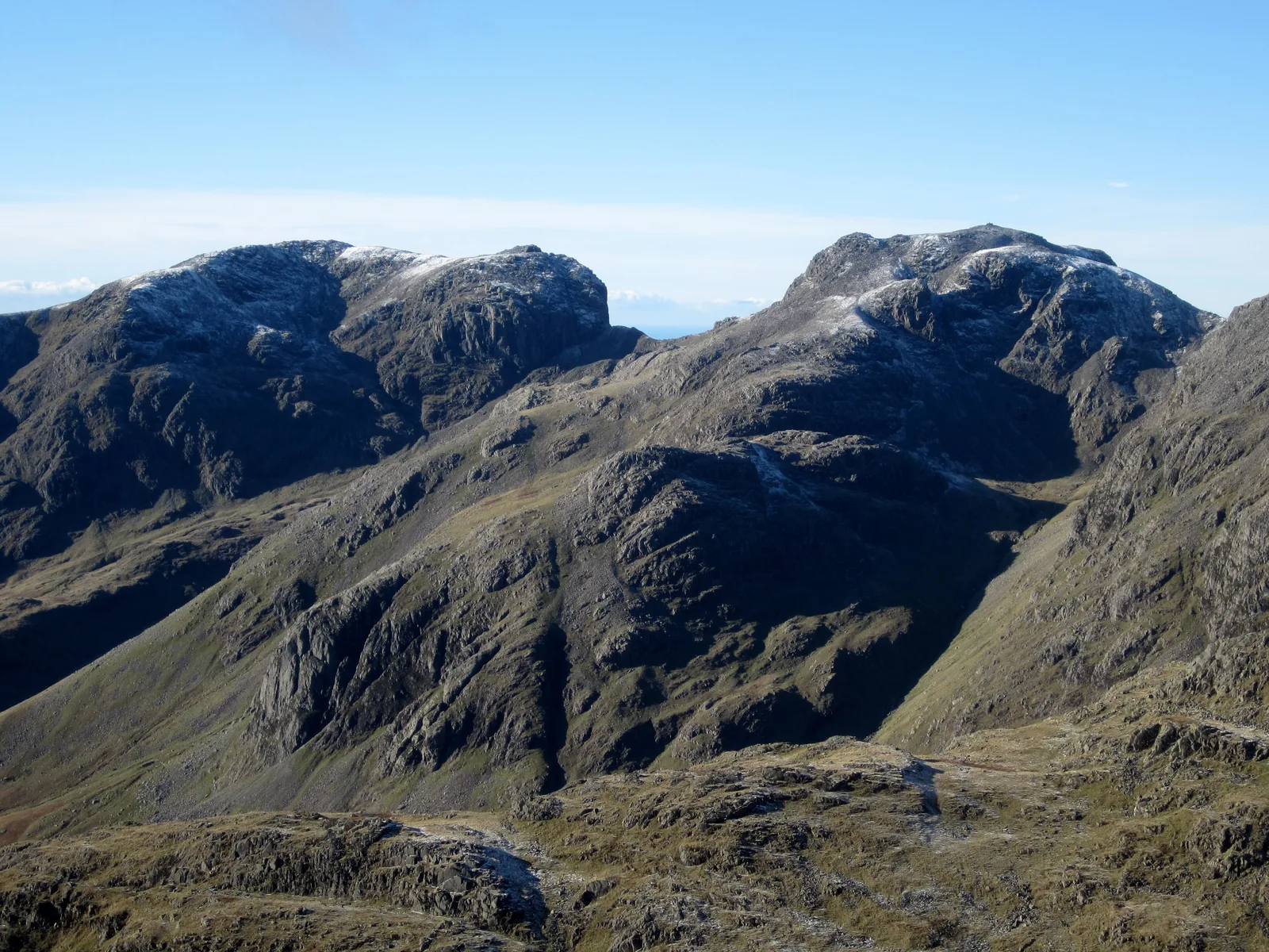 Scafell und Scafell Pike im Lake-District-Nationalpark, gesehen vom Gipfel des Bowfell, mit etwas Neuschnee auf den Gipfeln