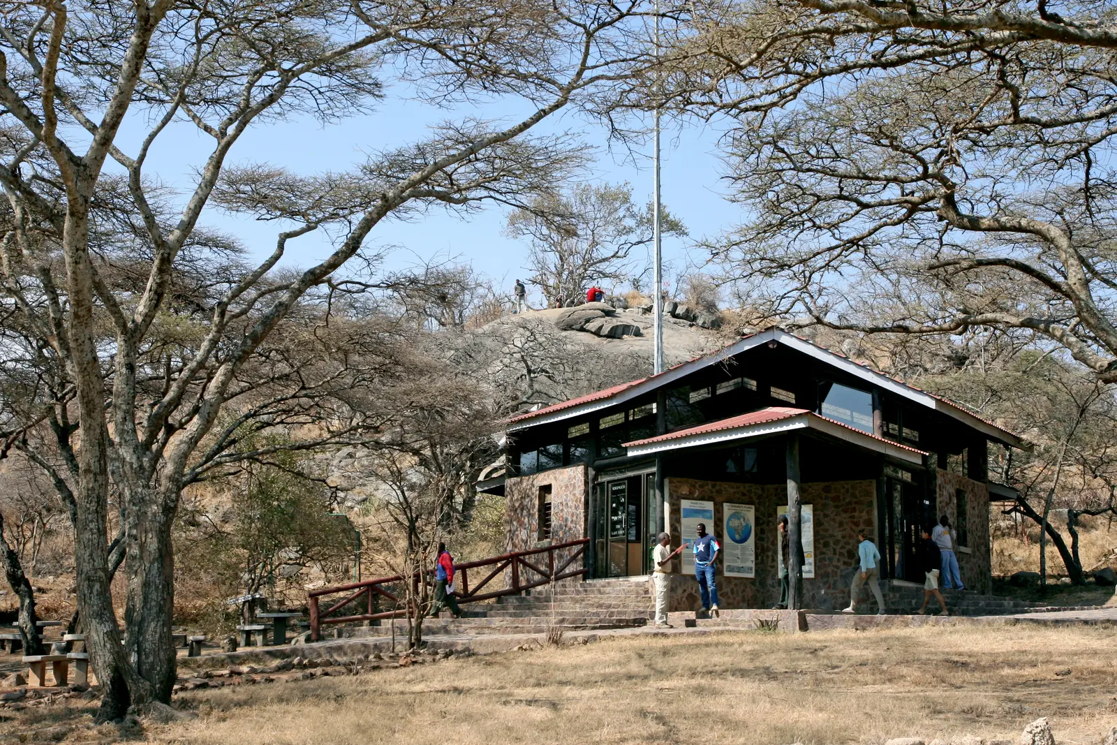 Das Torgebäude am Naabi Hill unter Akazien, Besucher an der Rampe