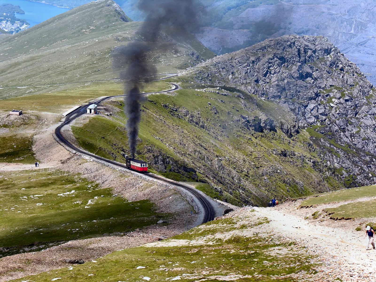 Ein Dampfzug der Snowdon Mountain Railway an der Station Clogwyn im Snowdonia-Nationalpark, dahinter der Berghang