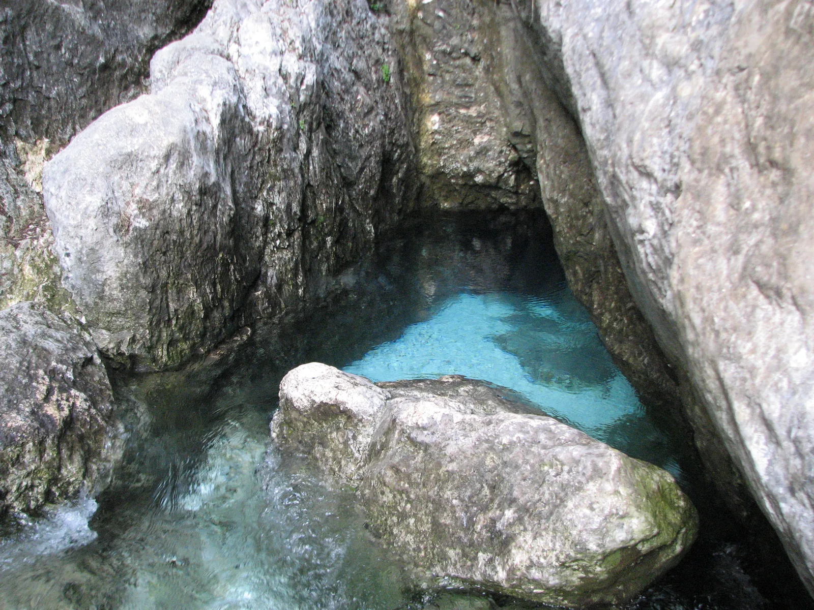 Die Soča tritt als klares, türkisfarbenes Wasser zwischen hellen Felsen aus