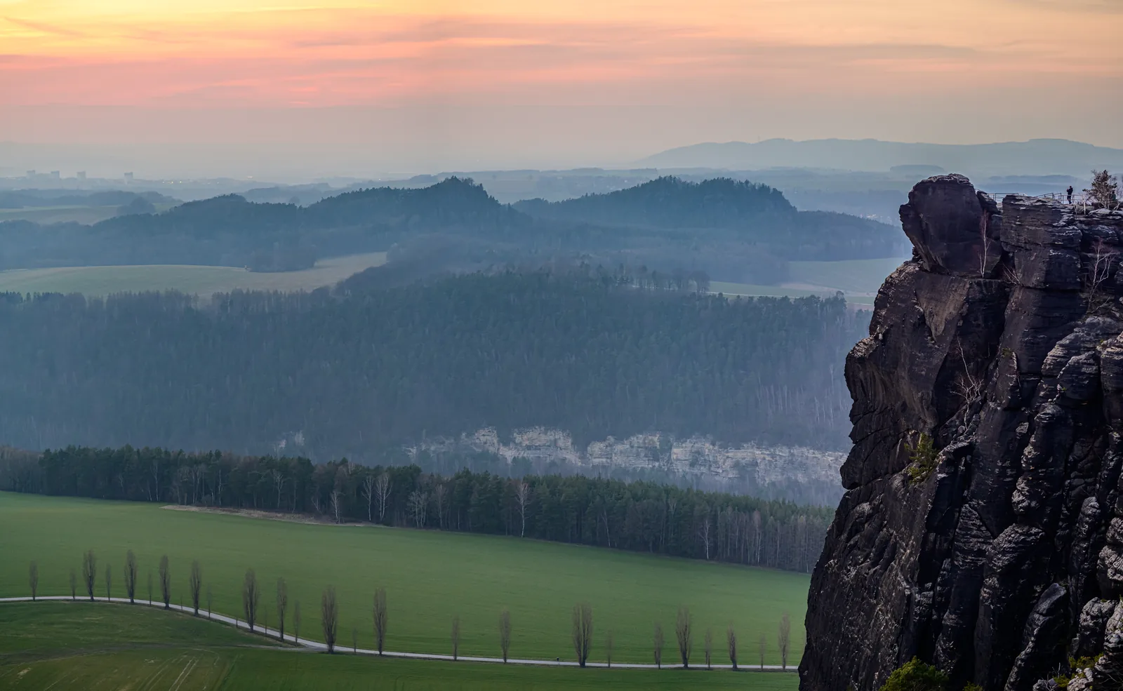 Blick vom Lilienstein bei Sonnenaufgang über gestaffelte Höhenzüge und Nebelfelder