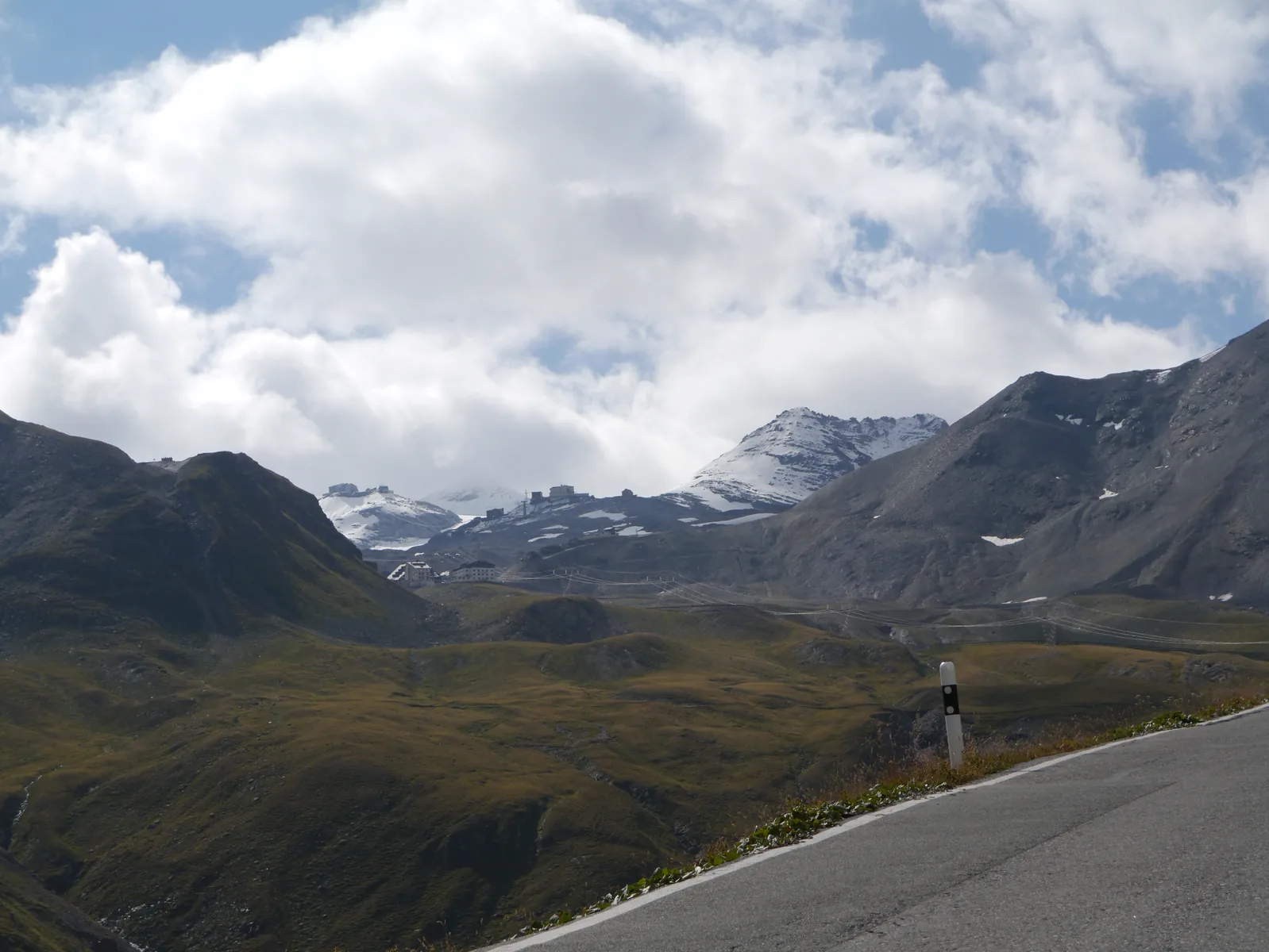 Blick vom Umbrailpass auf die Straße zum Stilfser Joch, dahinter Gipfel mit Schneefeldern