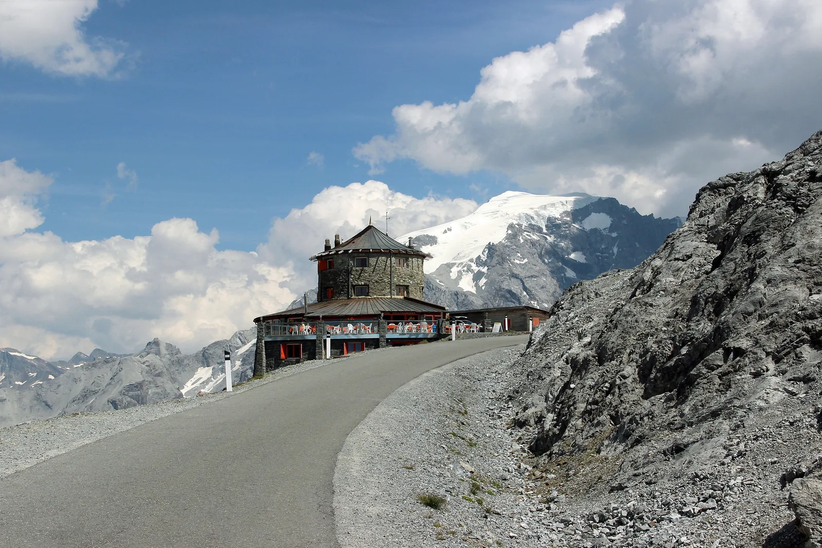 Die Straße an der Passhöhe des Stilfser Jochs mit dem Tibethaus, dahinter das vergletscherte Ortlermassiv
