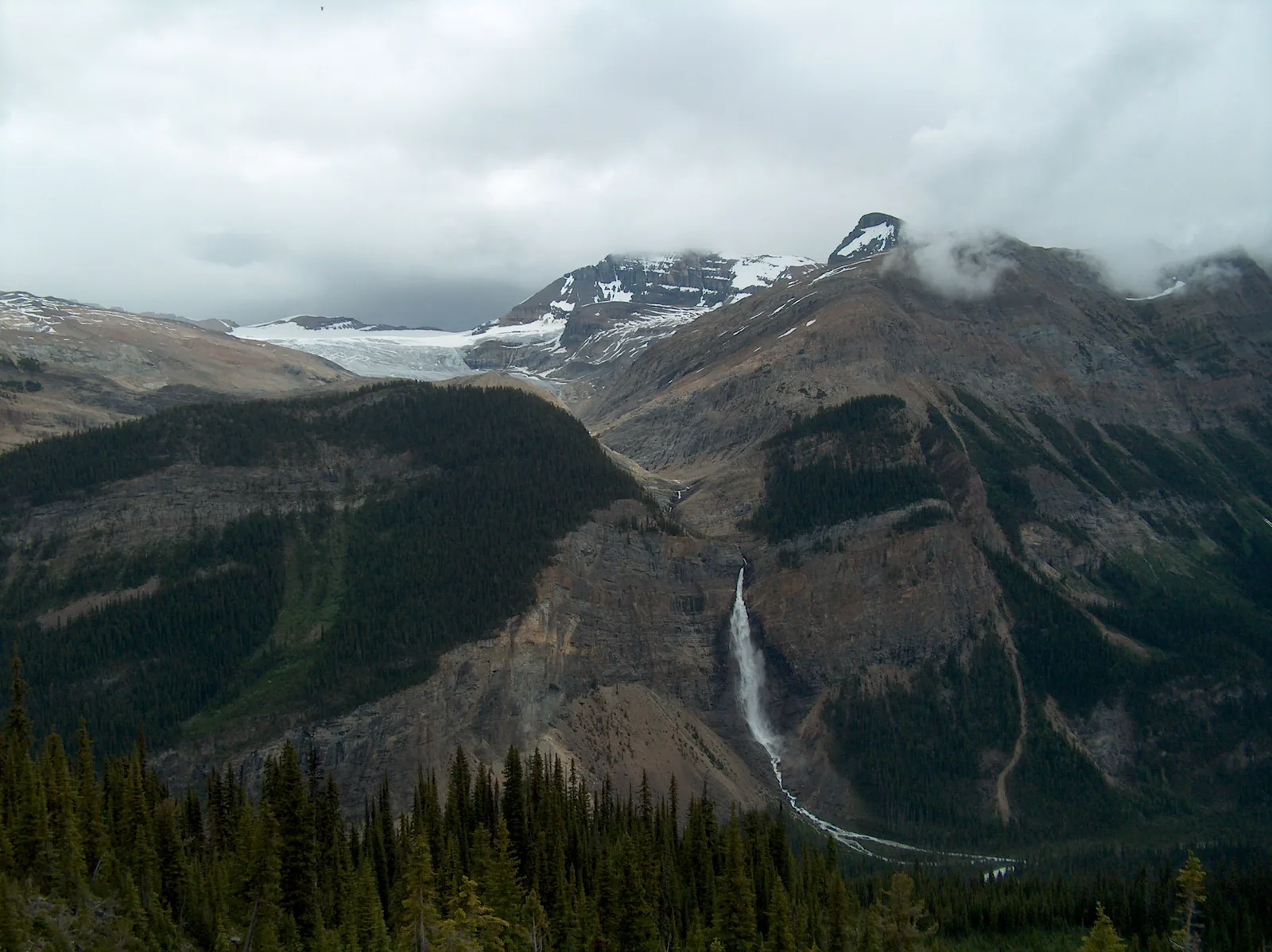 Blick von der Iceline auf die Takakkaw Falls im Yoho-Nationalpark, darüber der Daly-Gletscher unter Wolken.