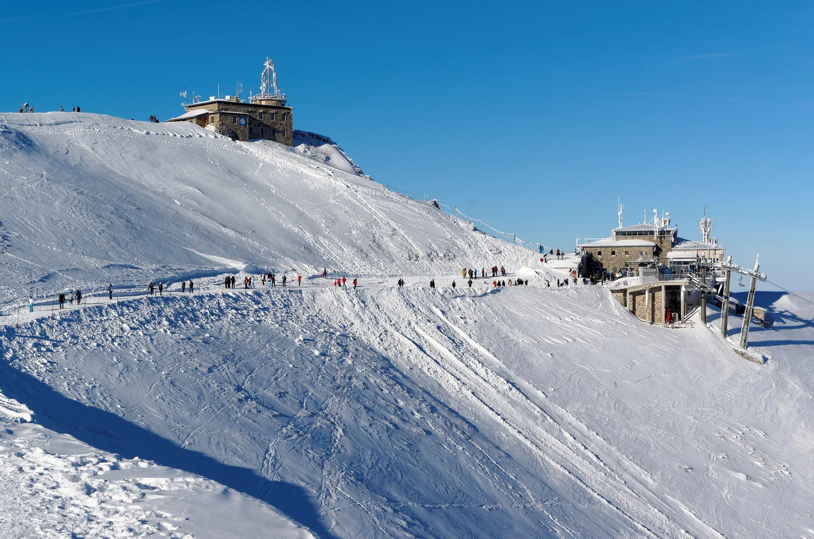 Das Wetterobservatorium auf dem Gipfel des Kasprowy Wierch und die Bergstation der Seilbahn im Schnee, Wanderer auf dem Kamm