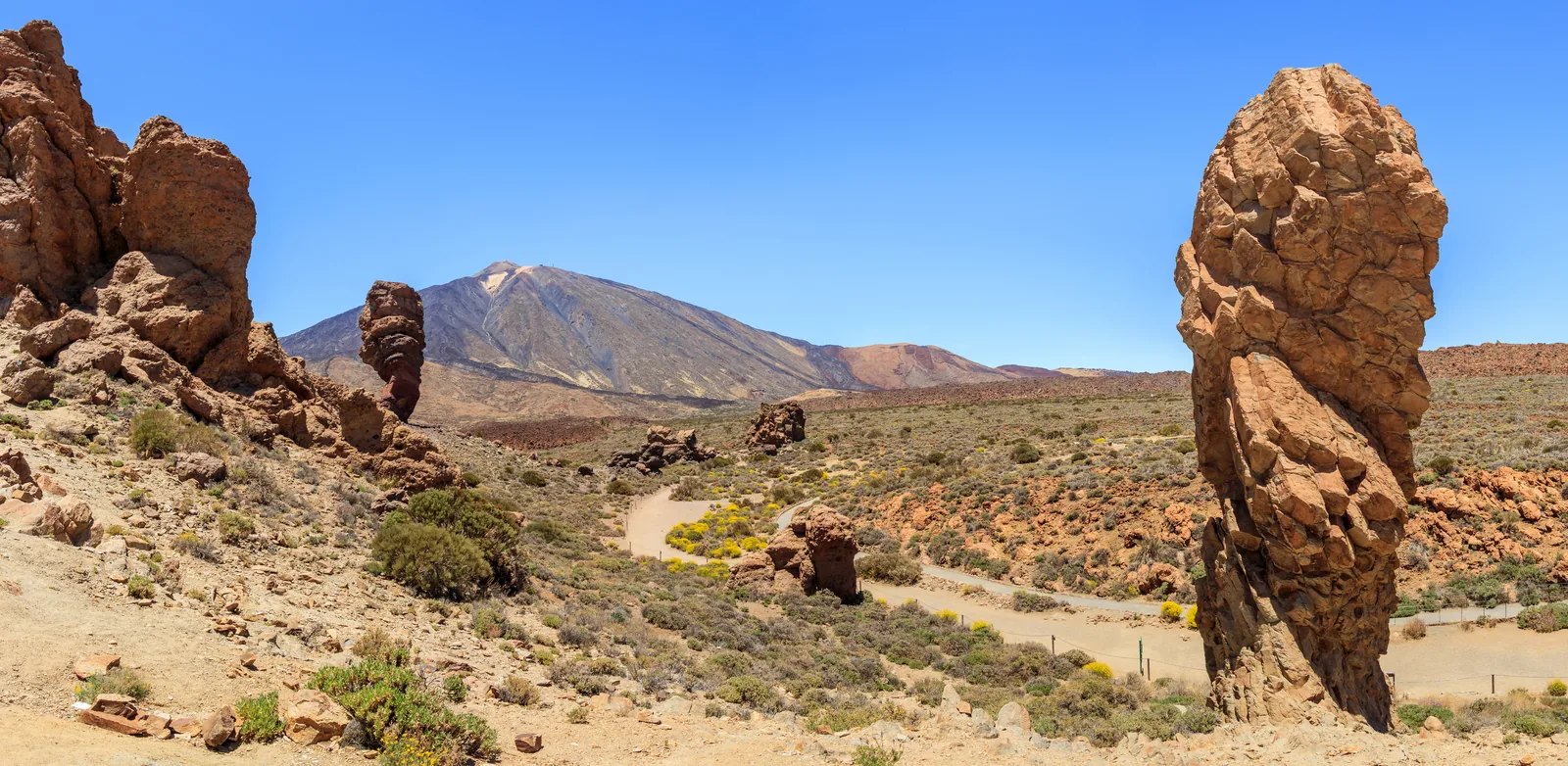 Die Felsgruppe Roques de García mit Roque Cinchado und Roque Torrotito, dahinter der Teide unter blauem Himmel