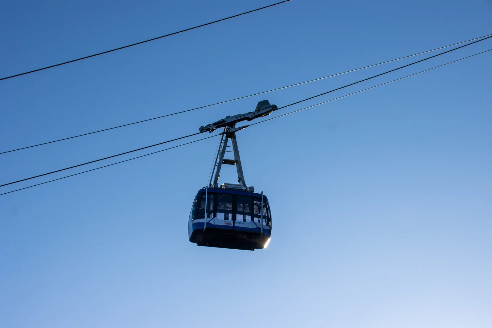 Eine Kabine der Teide-Seilbahn hängt vor blauem Himmel am Tragseil