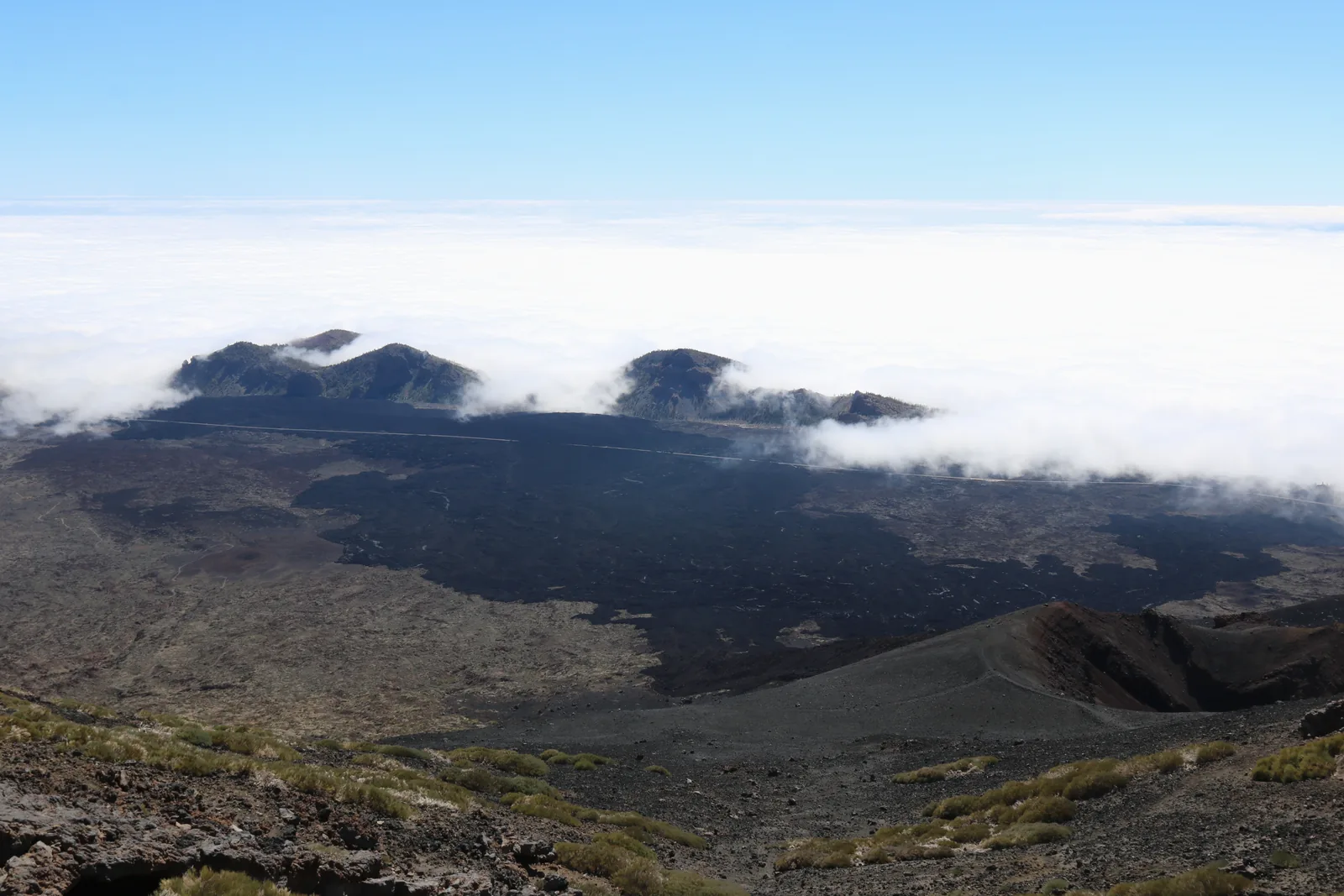 Wolken quellen über den Rand der Caldera, davor dunkle Lavafelder am Hang des Pico Viejo