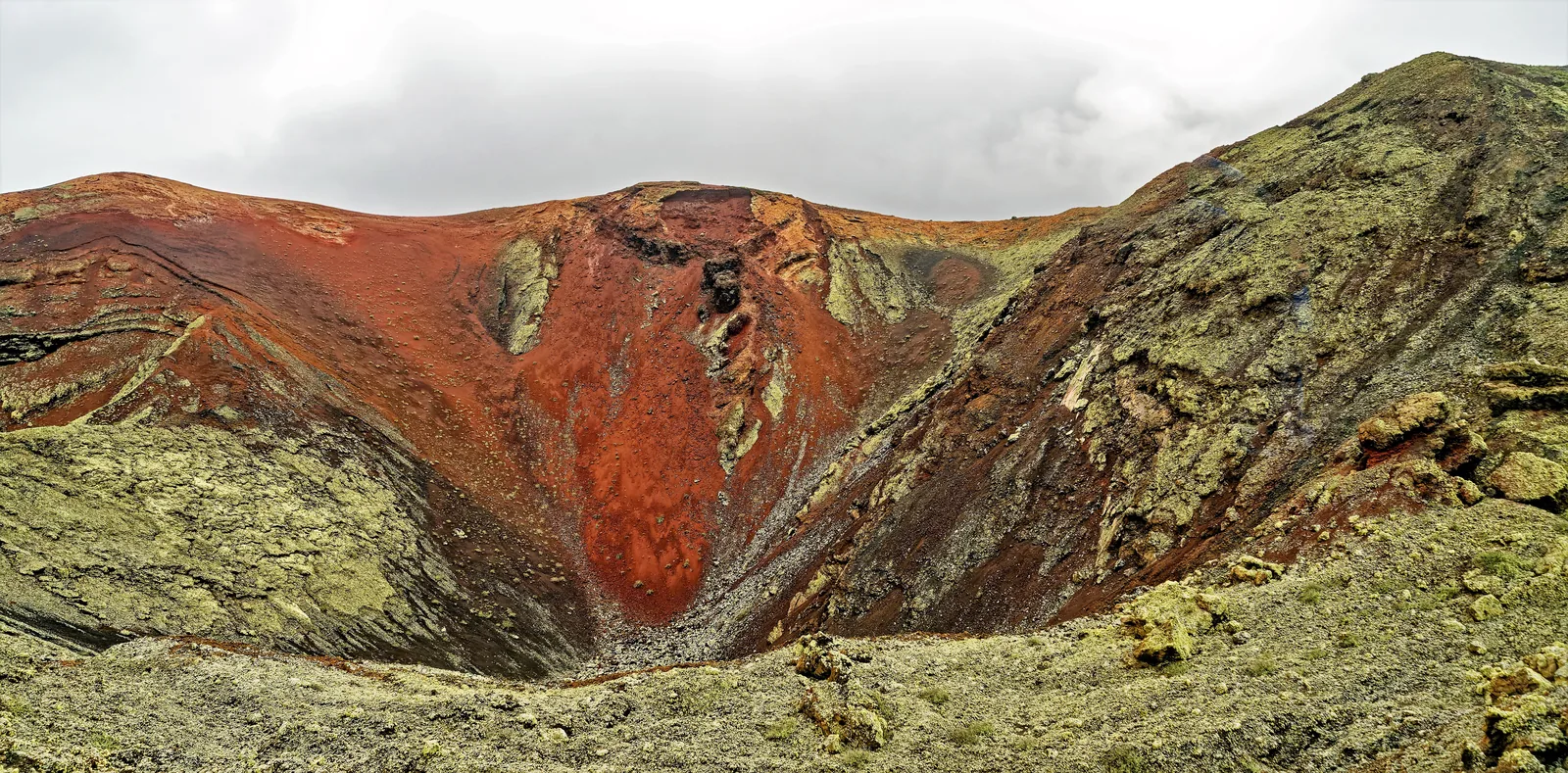 Ein rot und grün gefärbter Krater im Kern der Montañas del Fuego, gesehen von der Busroute