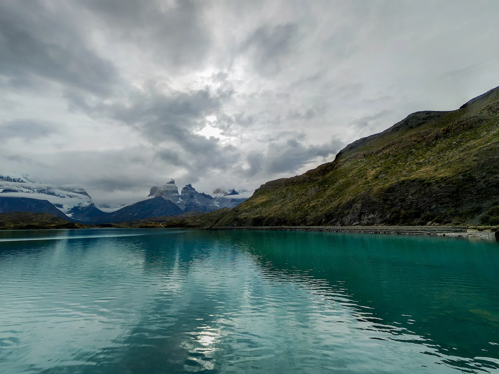 Der türkise Lago Pehoé im Nationalpark Torres del Paine unter Wolken, am Horizont das Paine-Massiv