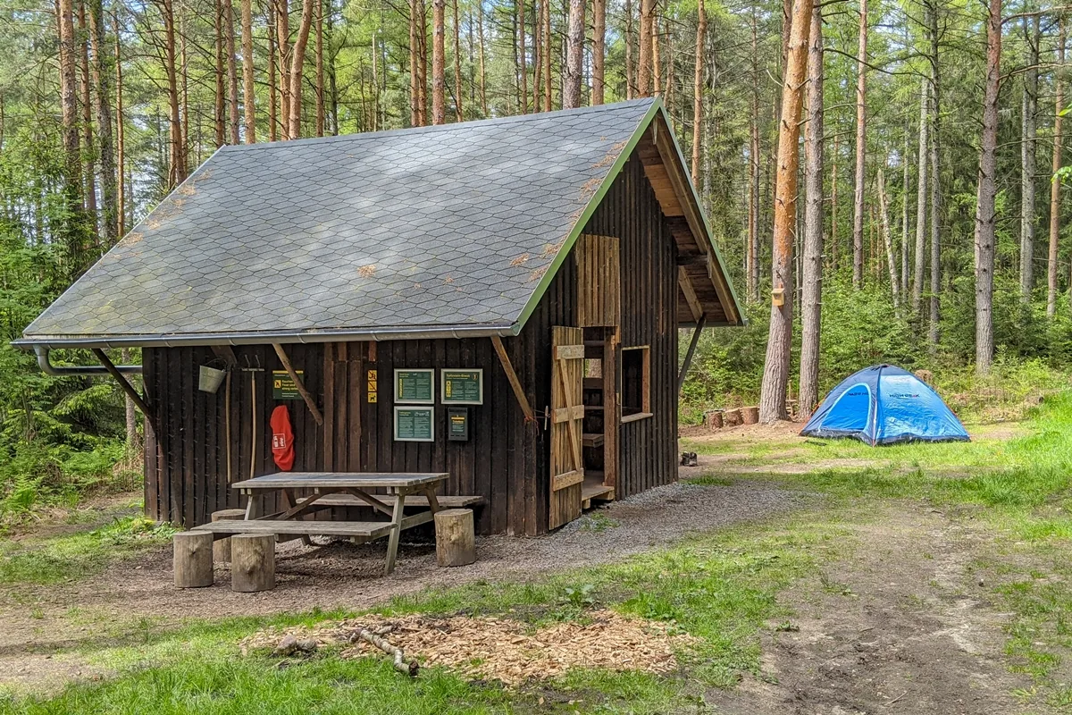 Trekkingplatz Spitzstein-Biwak am Forststeig Elbsandstein mit Schutzhütte, Sitzgruppe und Zelt im Kiefernwald