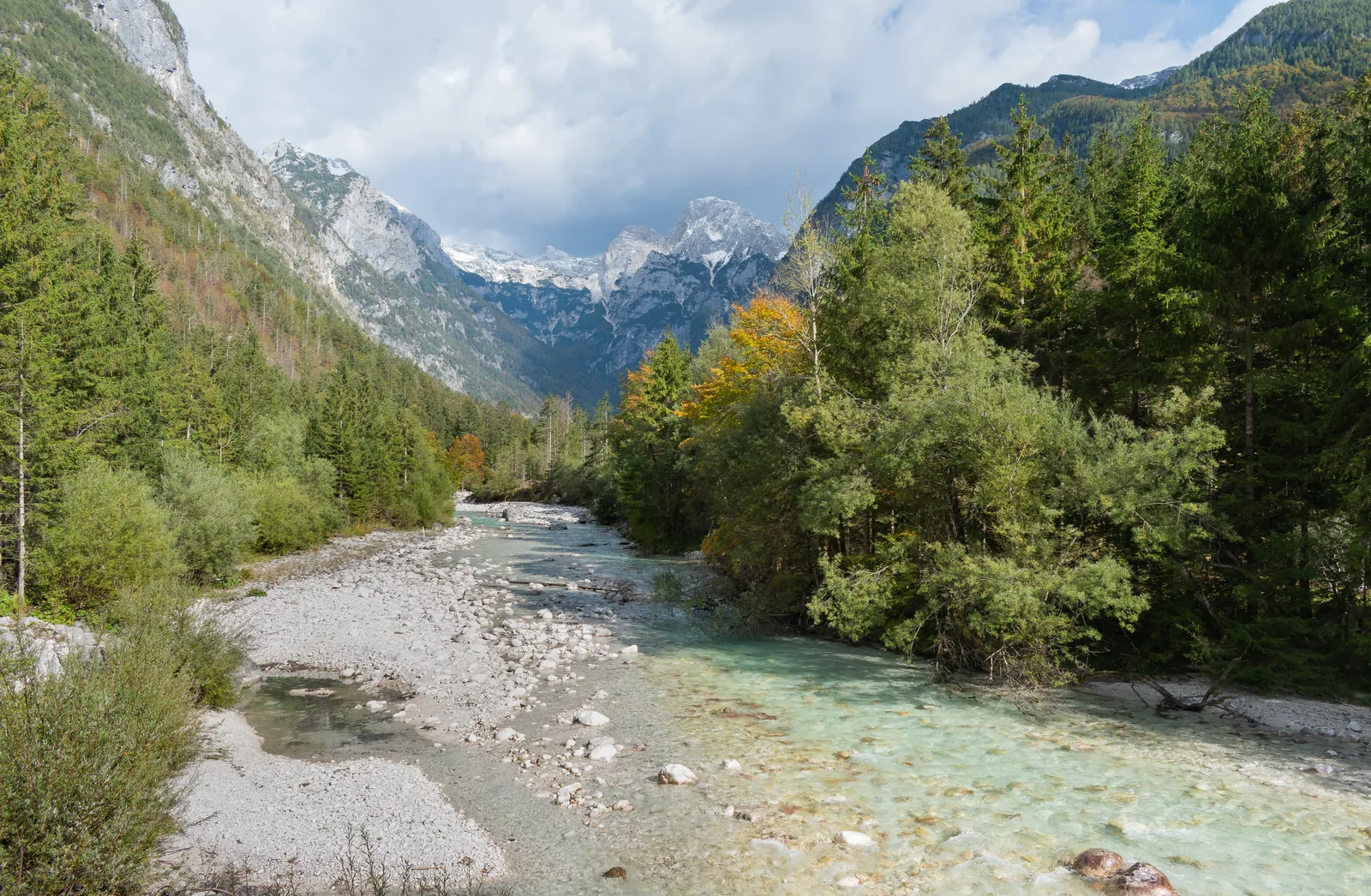 Die Soča im Trenta-Tal mit hellem Kiesbett und klarem, grünlichem Wasser vor den Julischen Alpen