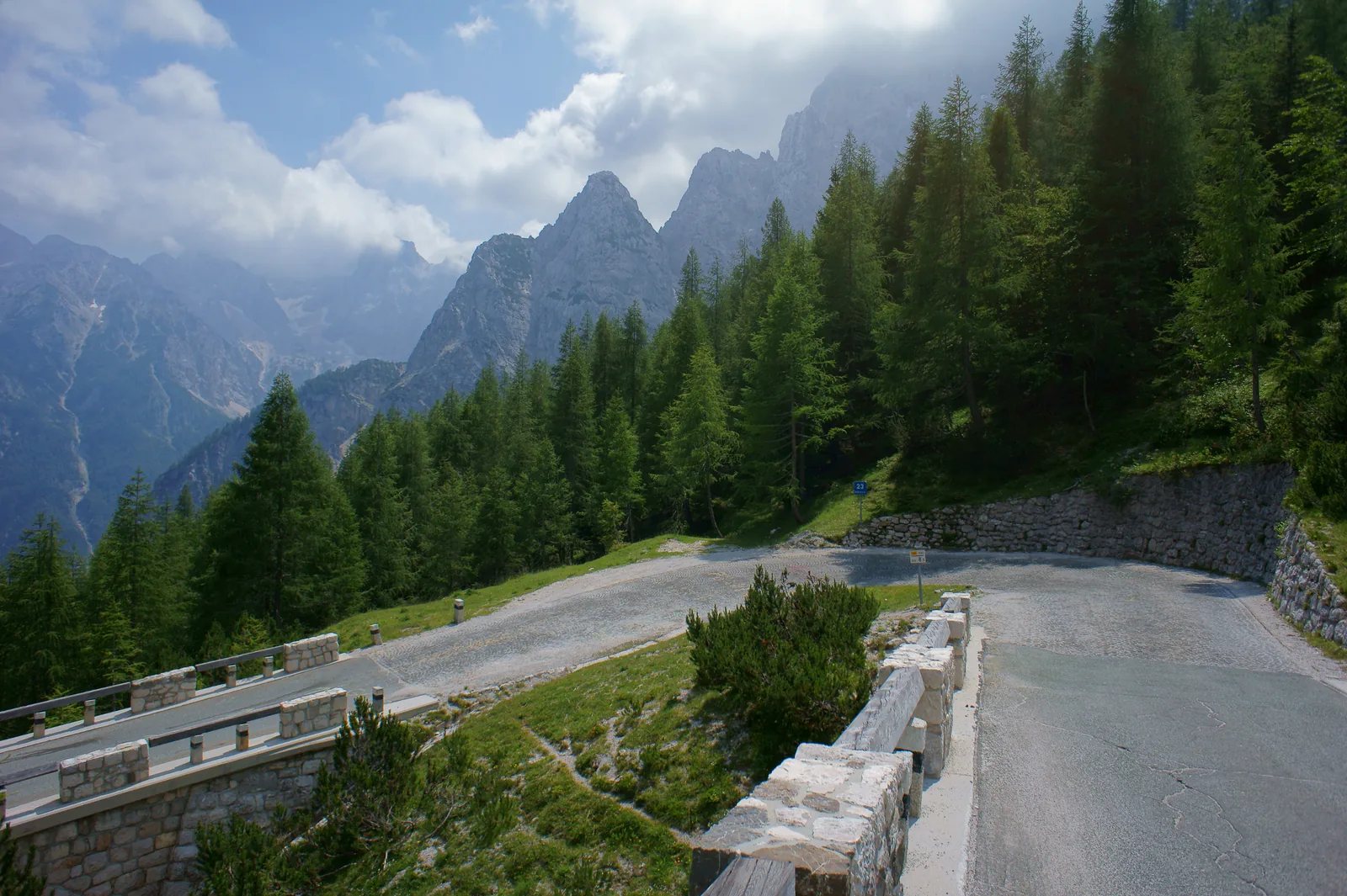Die Straße zum Vršič-Pass mit Steinmauer und Kehre vor zackigen Kalkgipfeln