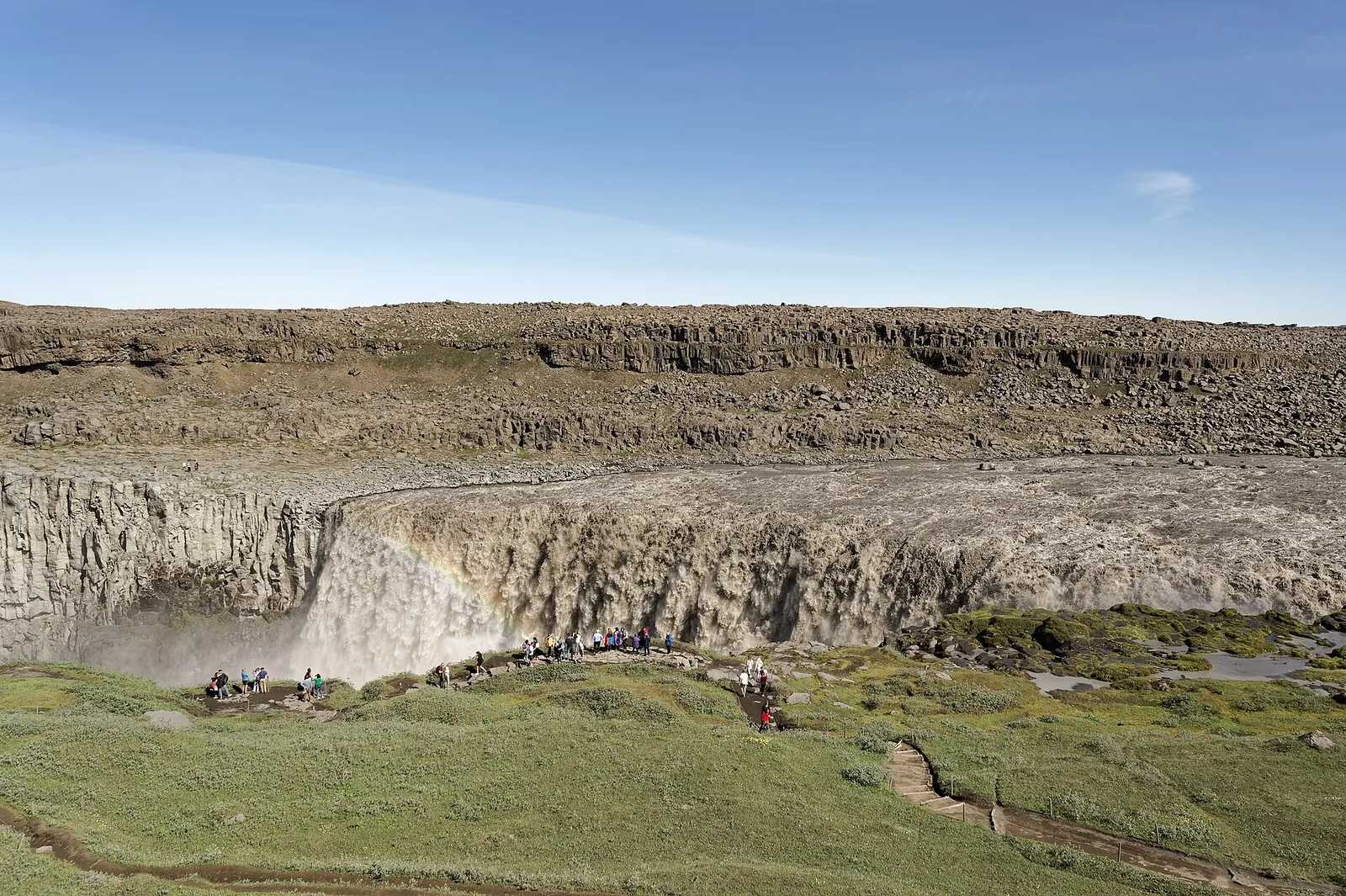 Der Dettifoss im Norden des Vatnajökull-Nationalparks: graue Wassermassen stürzen in eine breite Schlucht, Gischt steigt auf