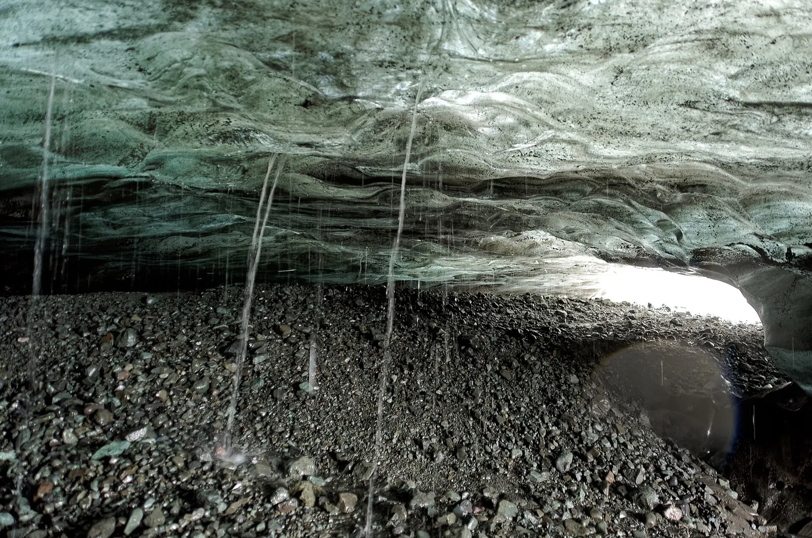 Blaues Eisgewölbe einer Eishöhle am Breiðamerkurjökull im Vatnajökull-Nationalpark, am Boden Geröll und Schmelzwasser