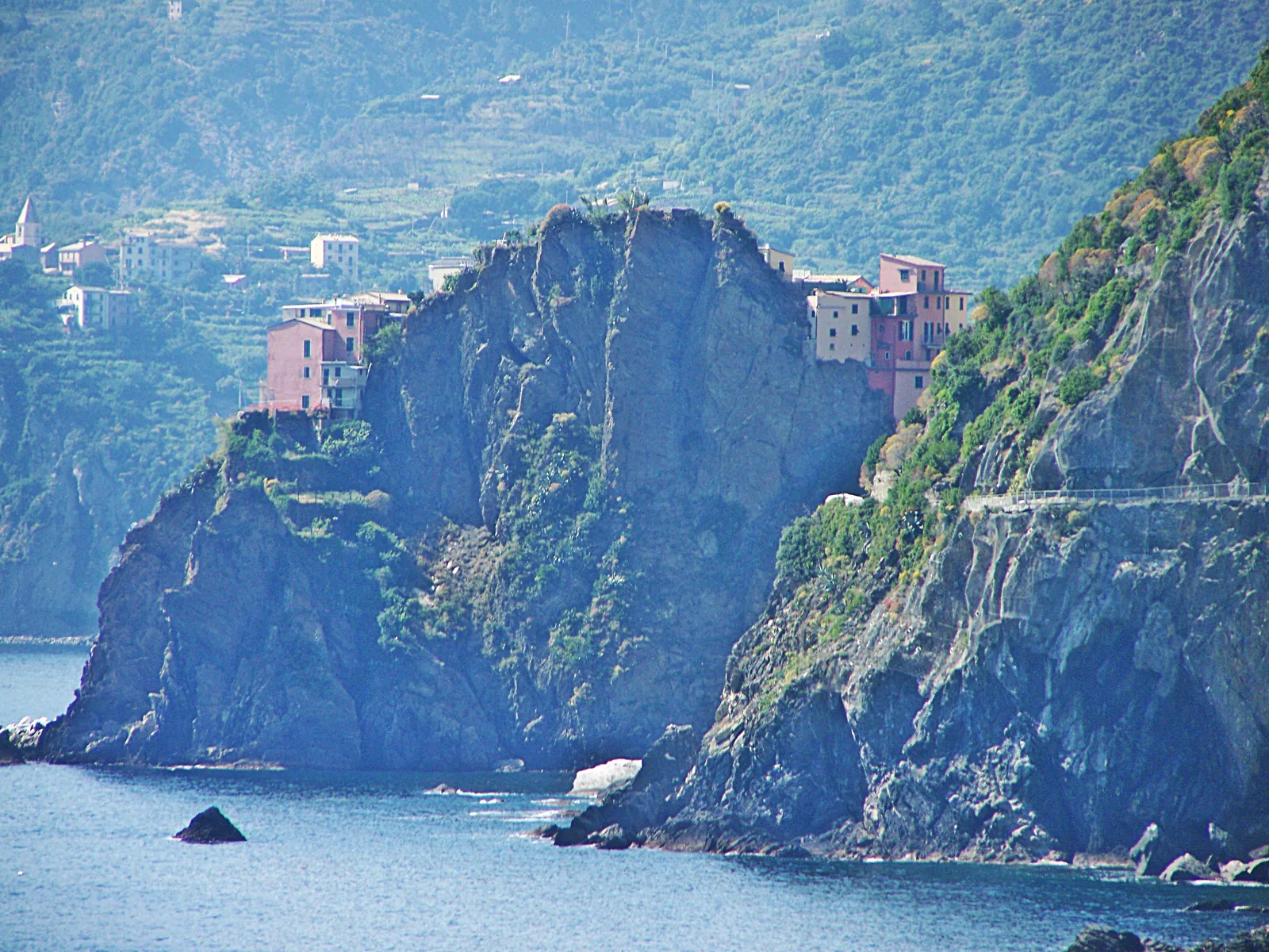 Manarola auf einem Felsvorsprung über dem Meer, rechts an der Steilküste der Verlauf der Via dell'Amore von Riomaggiore