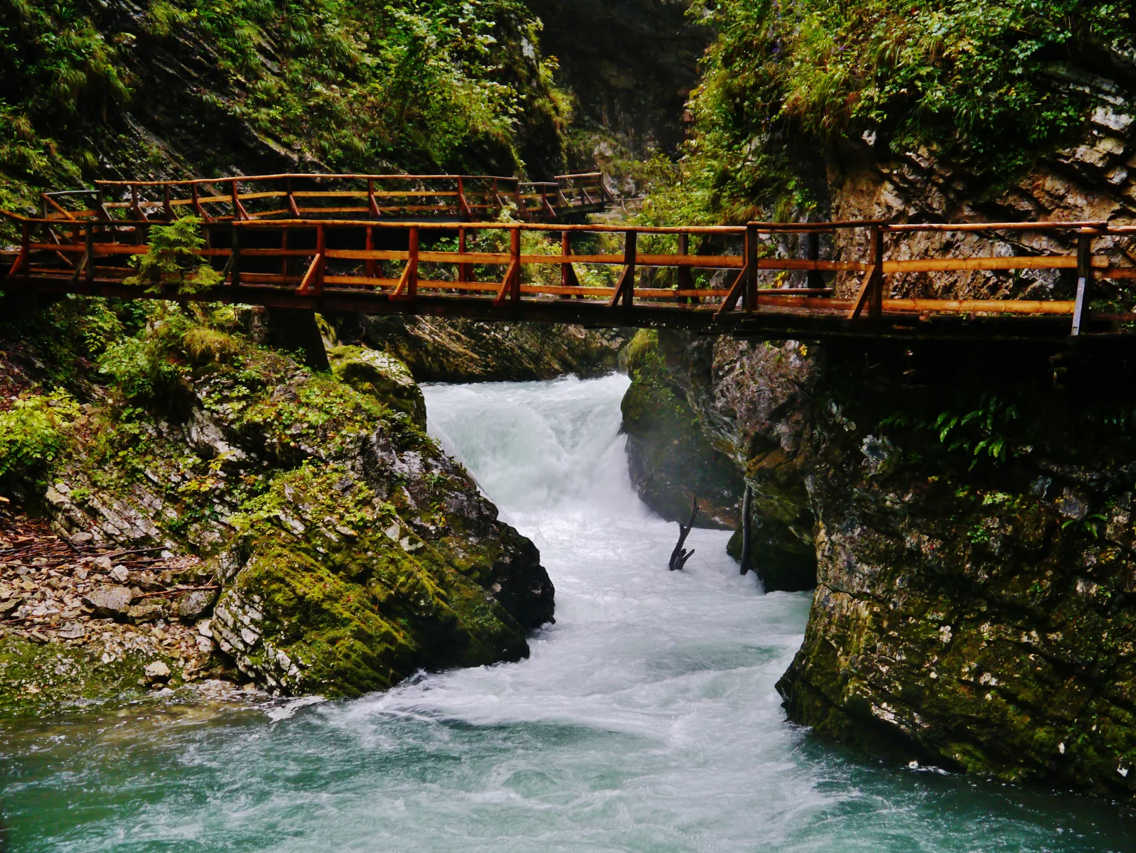 Brücke aus Holz über schäumendem Wasser in der engen Klamm