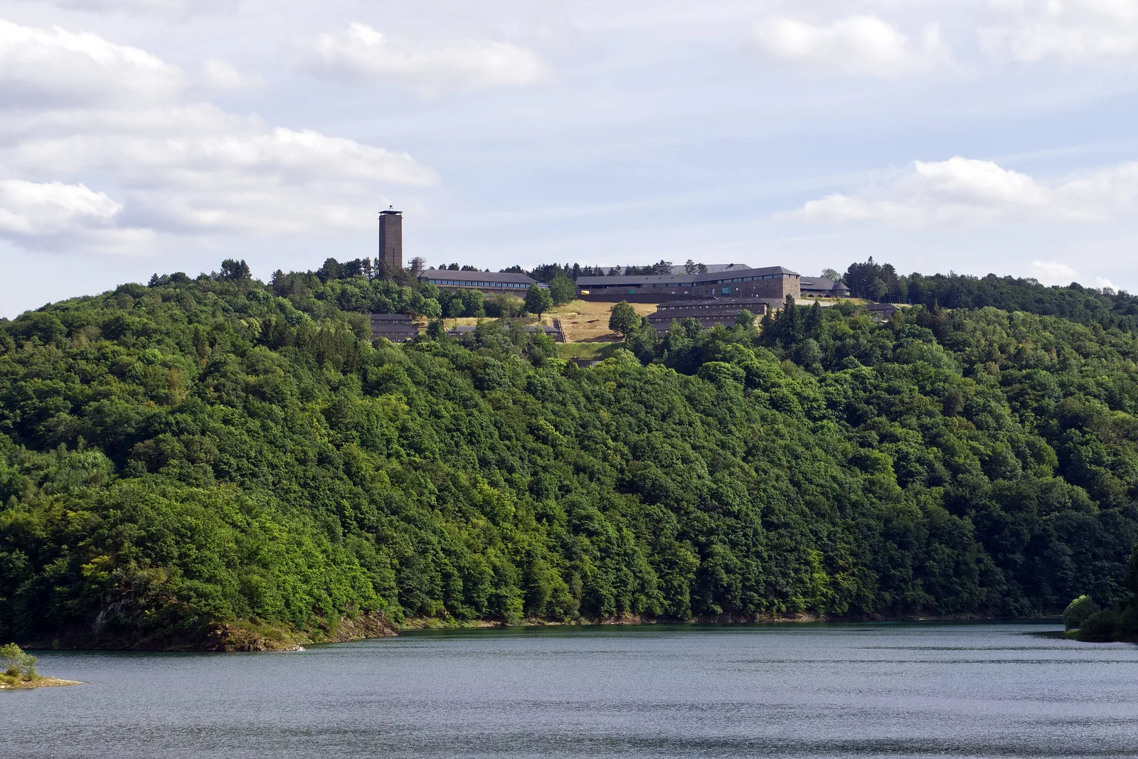 Vogelsang IP mit Turm auf dem bewaldeten Höhenrücken über dem Urftsee, vom Wasser aus gesehen