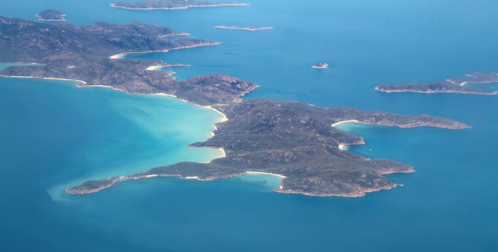 Die Whitsunday Islands im Great Barrier Reef aus der Luft: bewaldete Inseln mit weißen Stränden in türkisem Meer